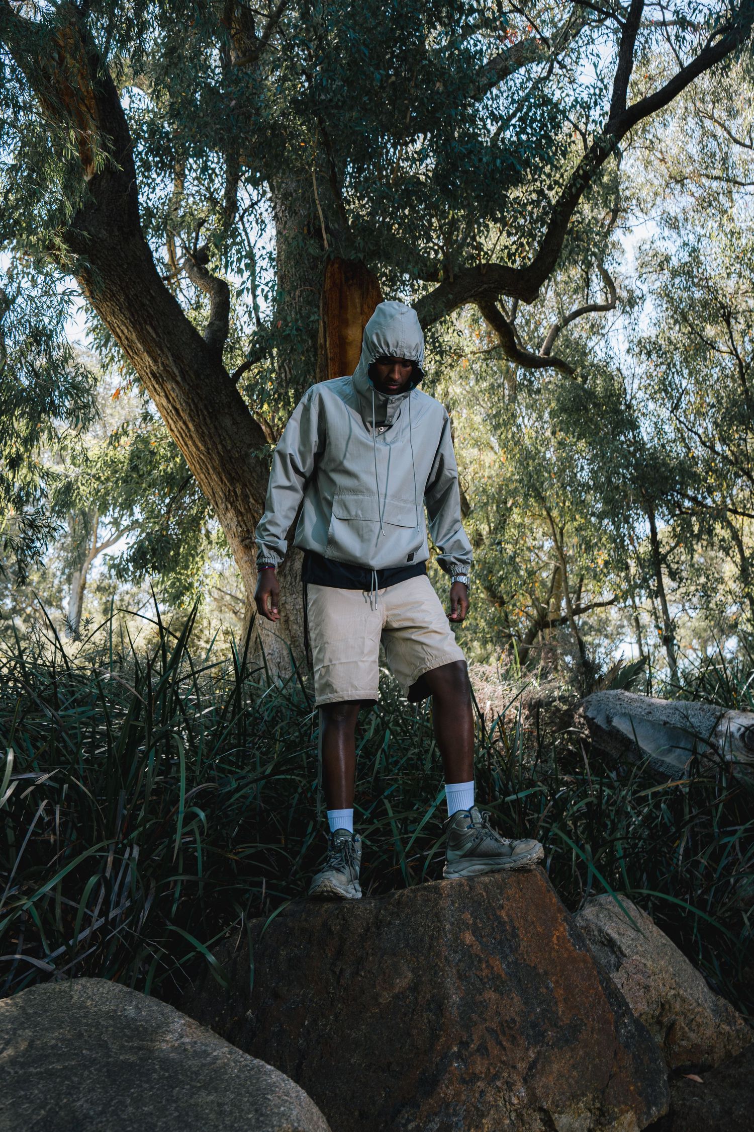 Person in casual wear standing on rock in natural wooded setting.