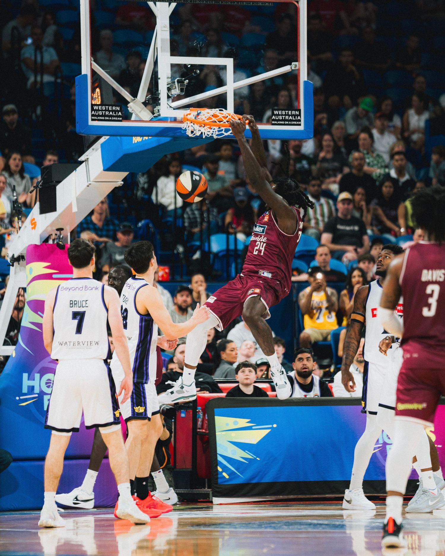 Basketball player performing a powerful slam dunk during an intense game.