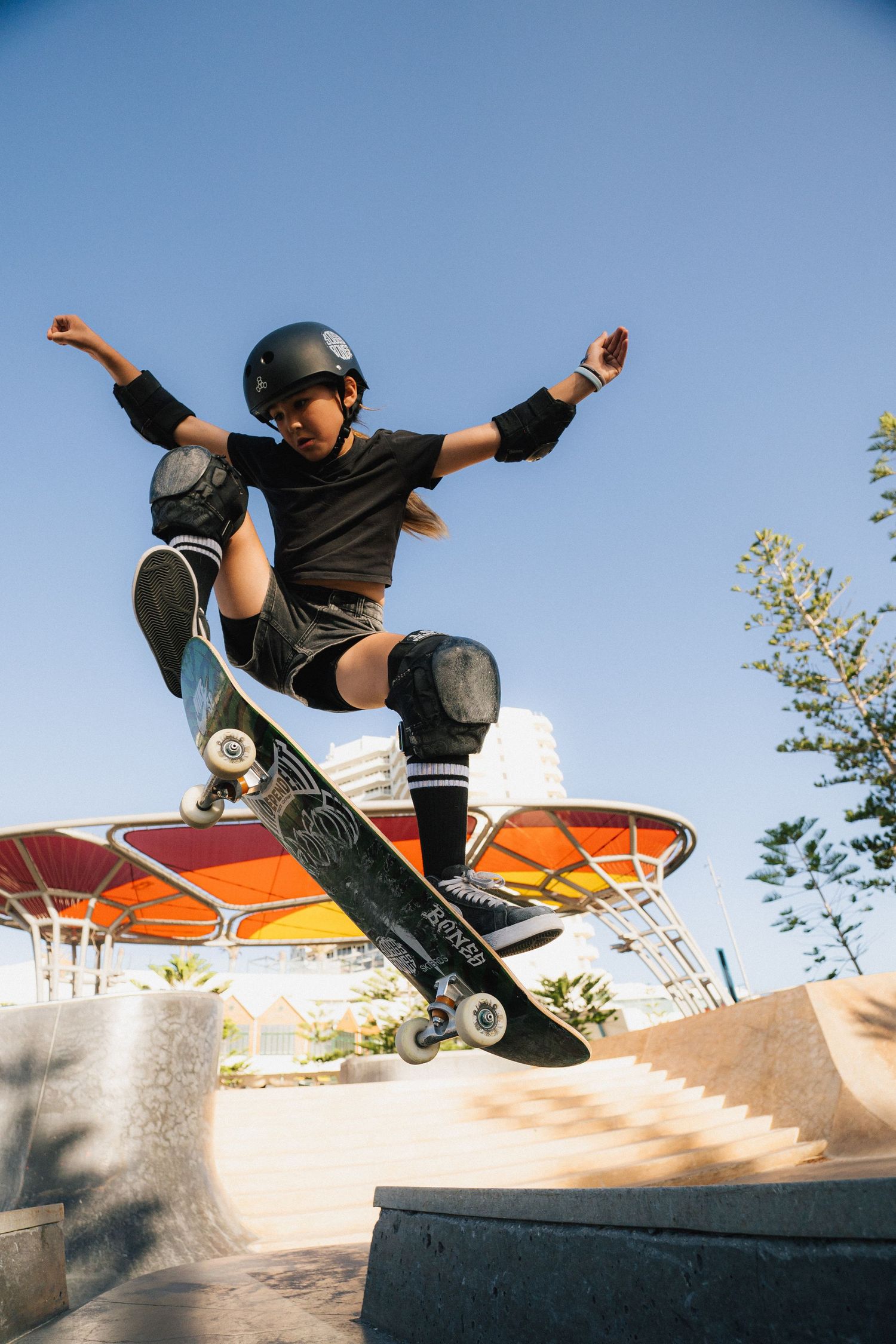 Skateboarder performing an aerial trick on a ramp against a blue sky.