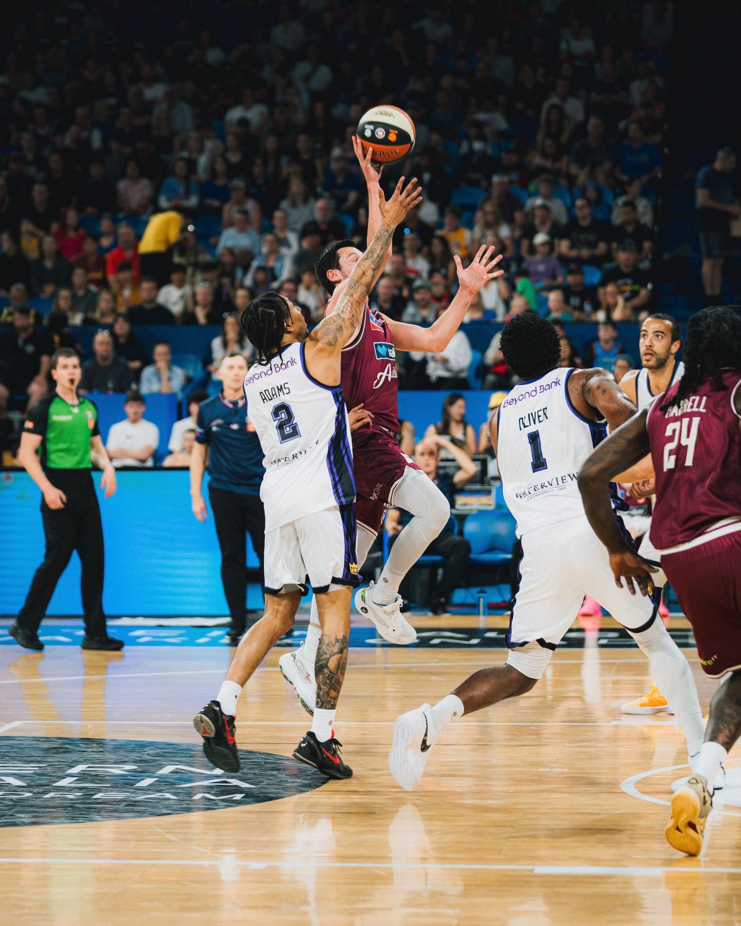 Basketball players leap for the ball during an intense play.