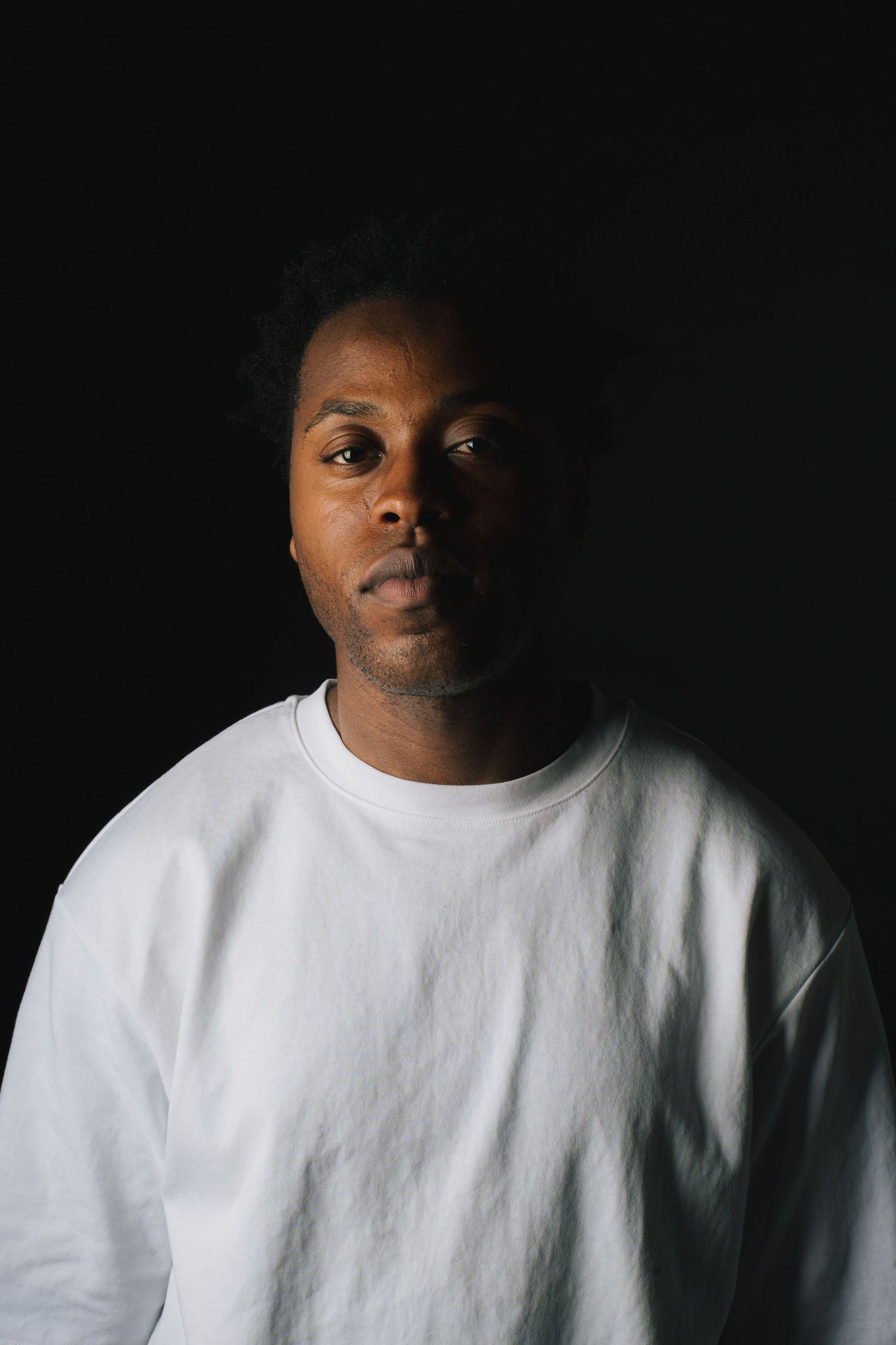 Portrait sequence in dramatic lighting showing a subject in a white t-shirt against a black background.