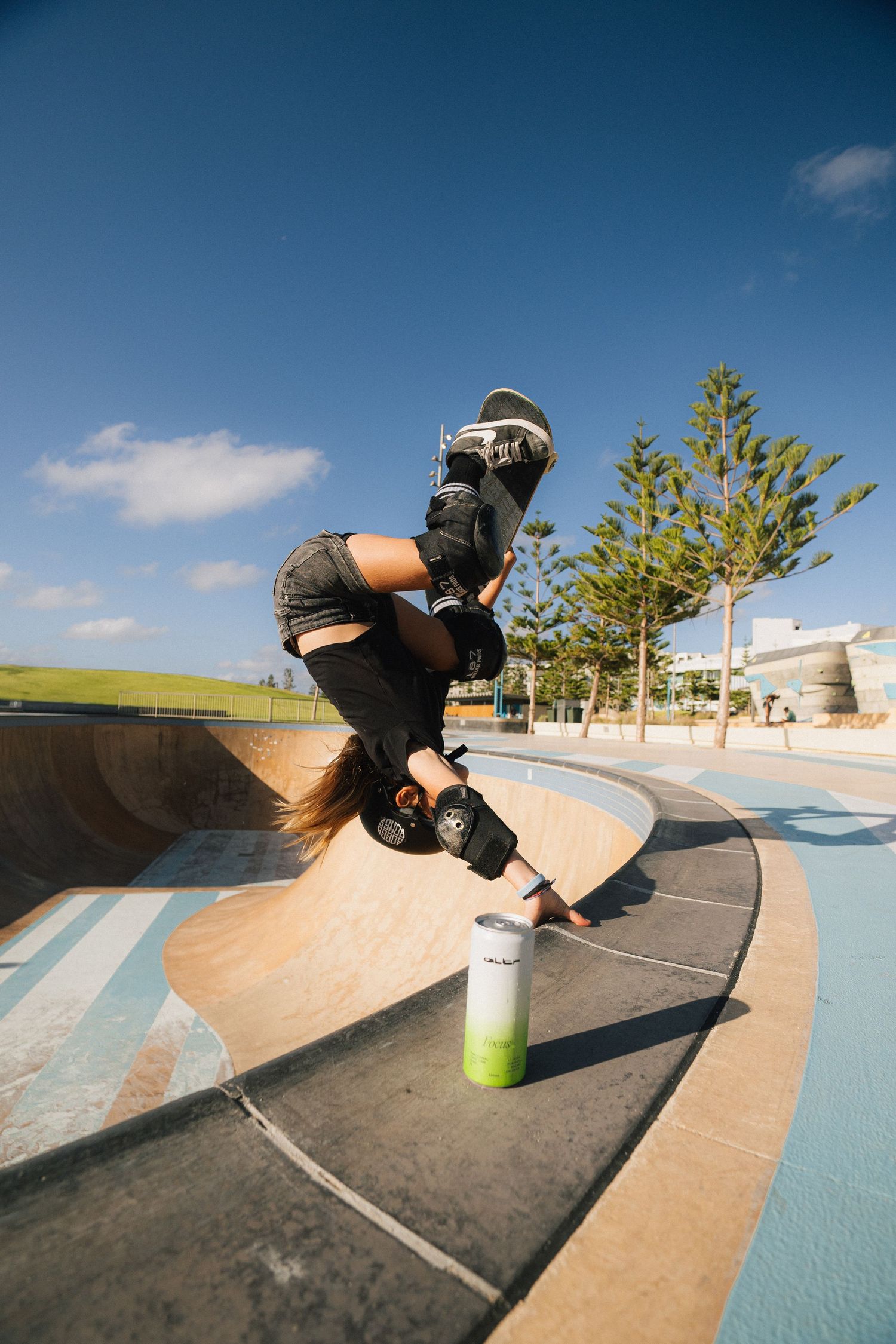 Skateboarder performing trick on curved ramp at outdoor skate park.