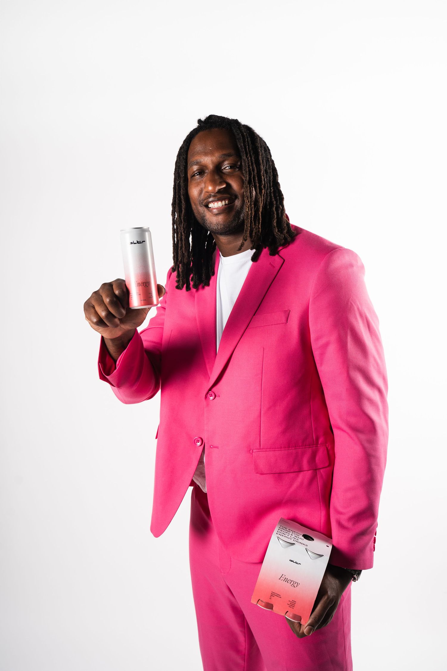 Person in bright pink business suit holding a drink can and marketing materials against white background.