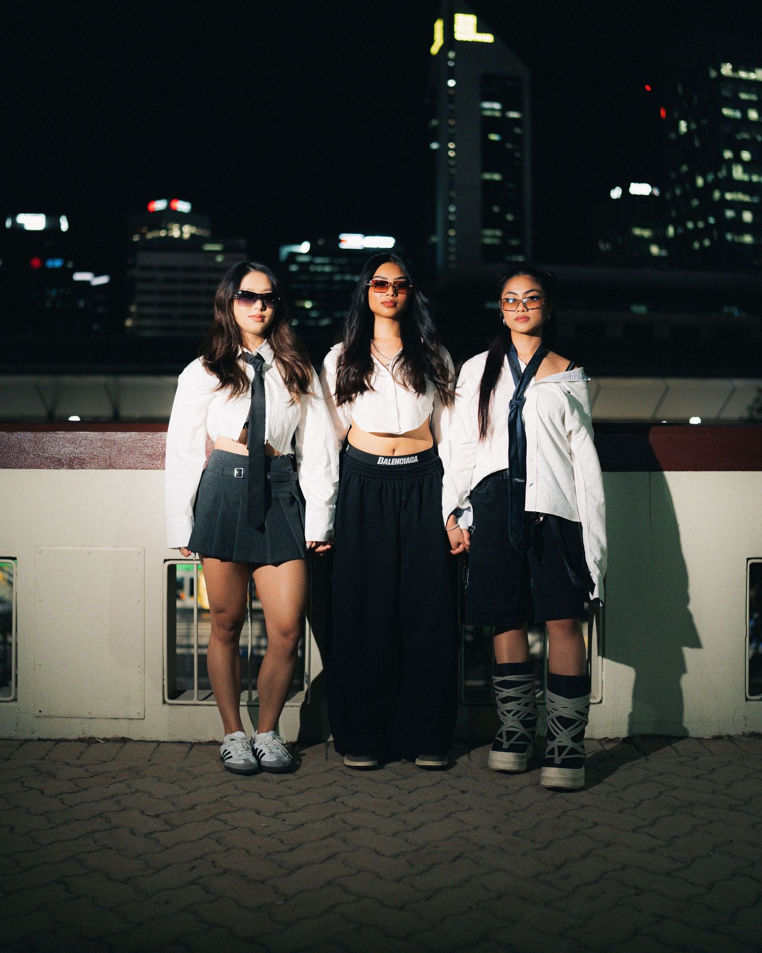 Group poses against urban nighttime skyline wearing contrasting black and white outfits.