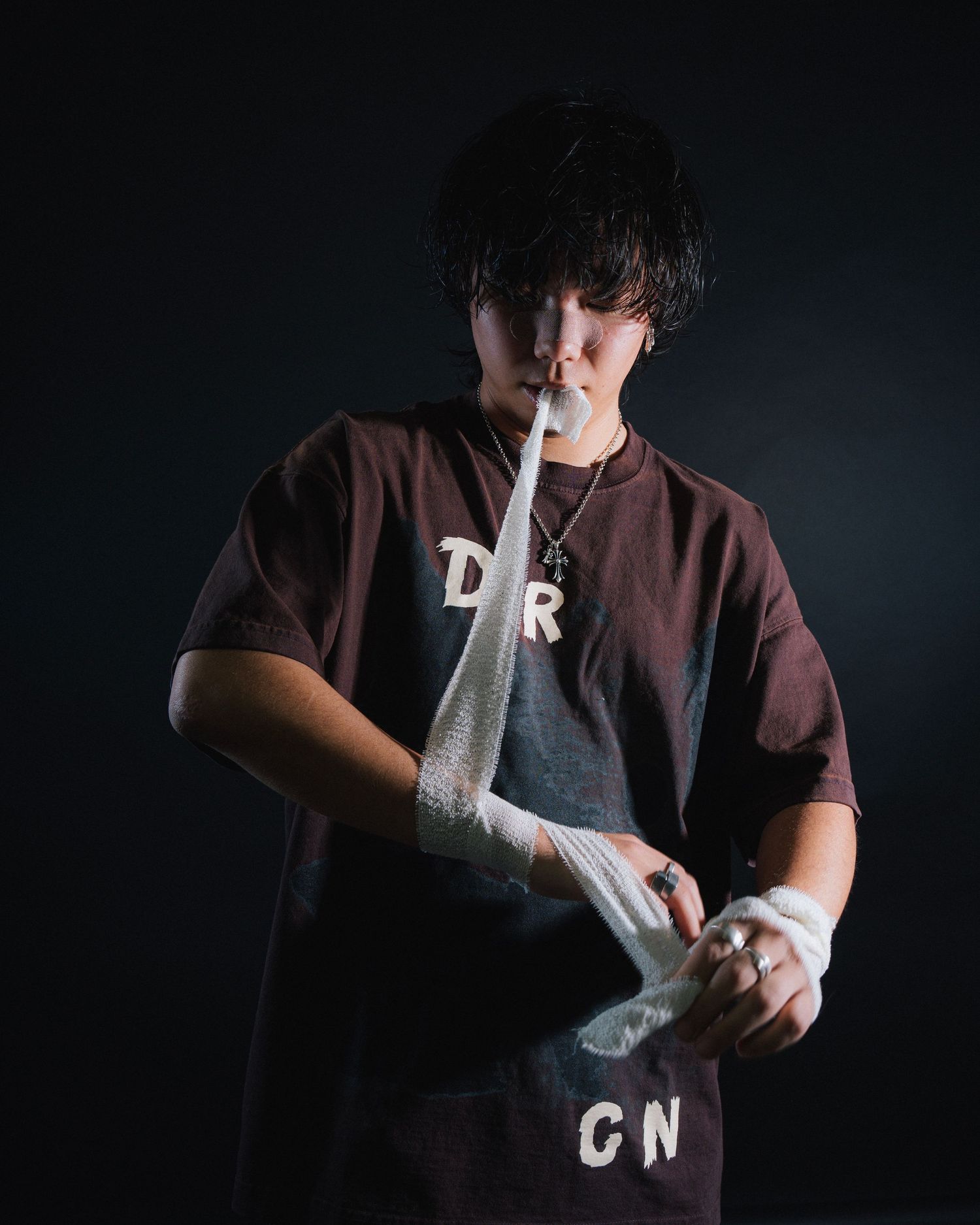 Person in brown t-shirt wrapping hands with athletic tape against dark background.