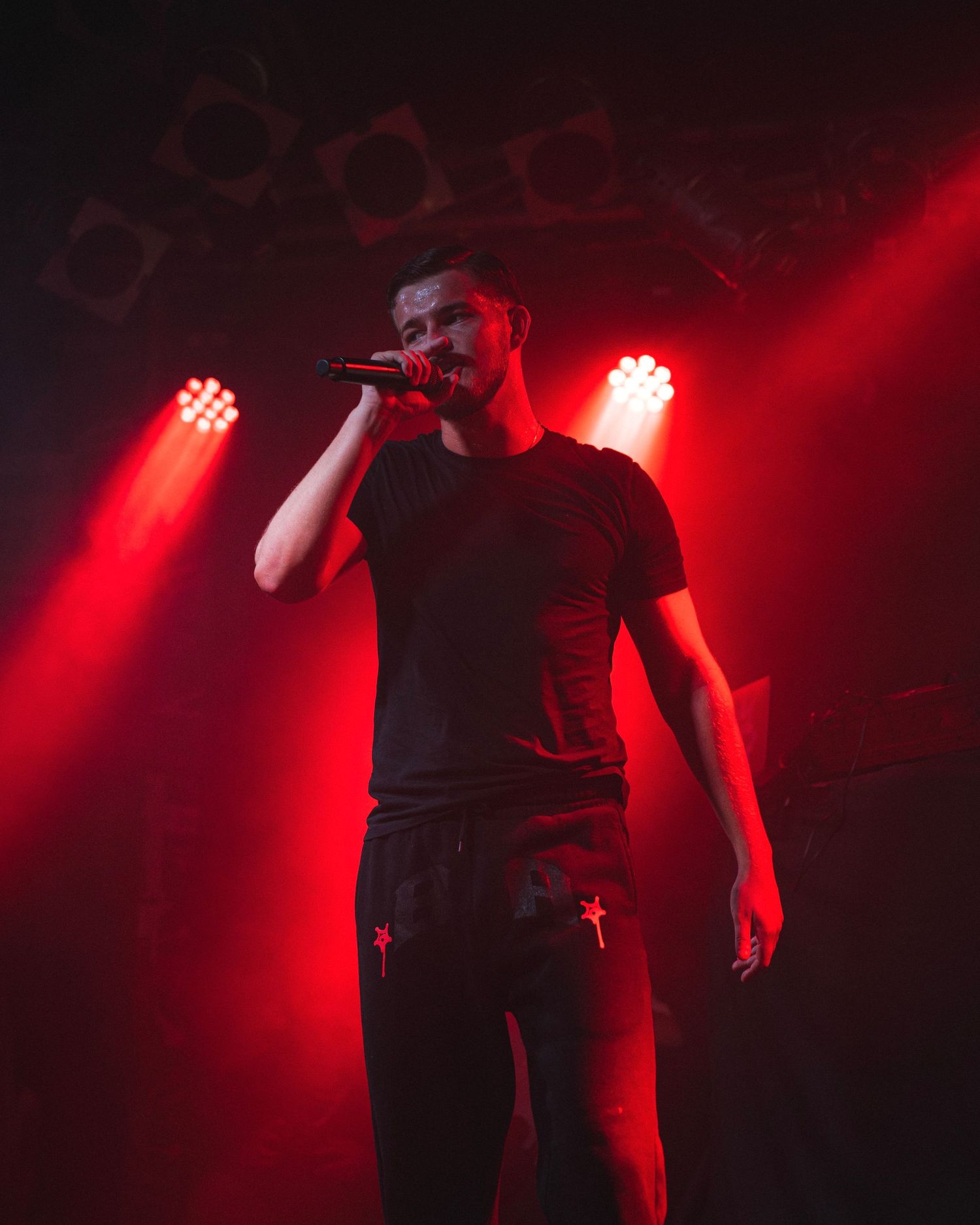 Performer silhouetted against dramatic red stage lighting during concert performance.