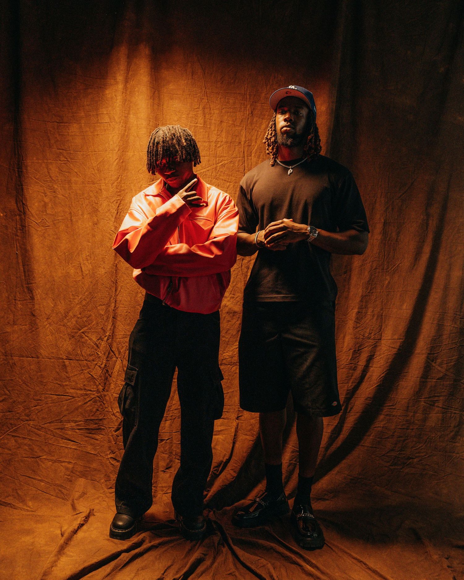 Two silhouetted figures stand against a warm orange backdrop in a sequence of expressive dance movements.