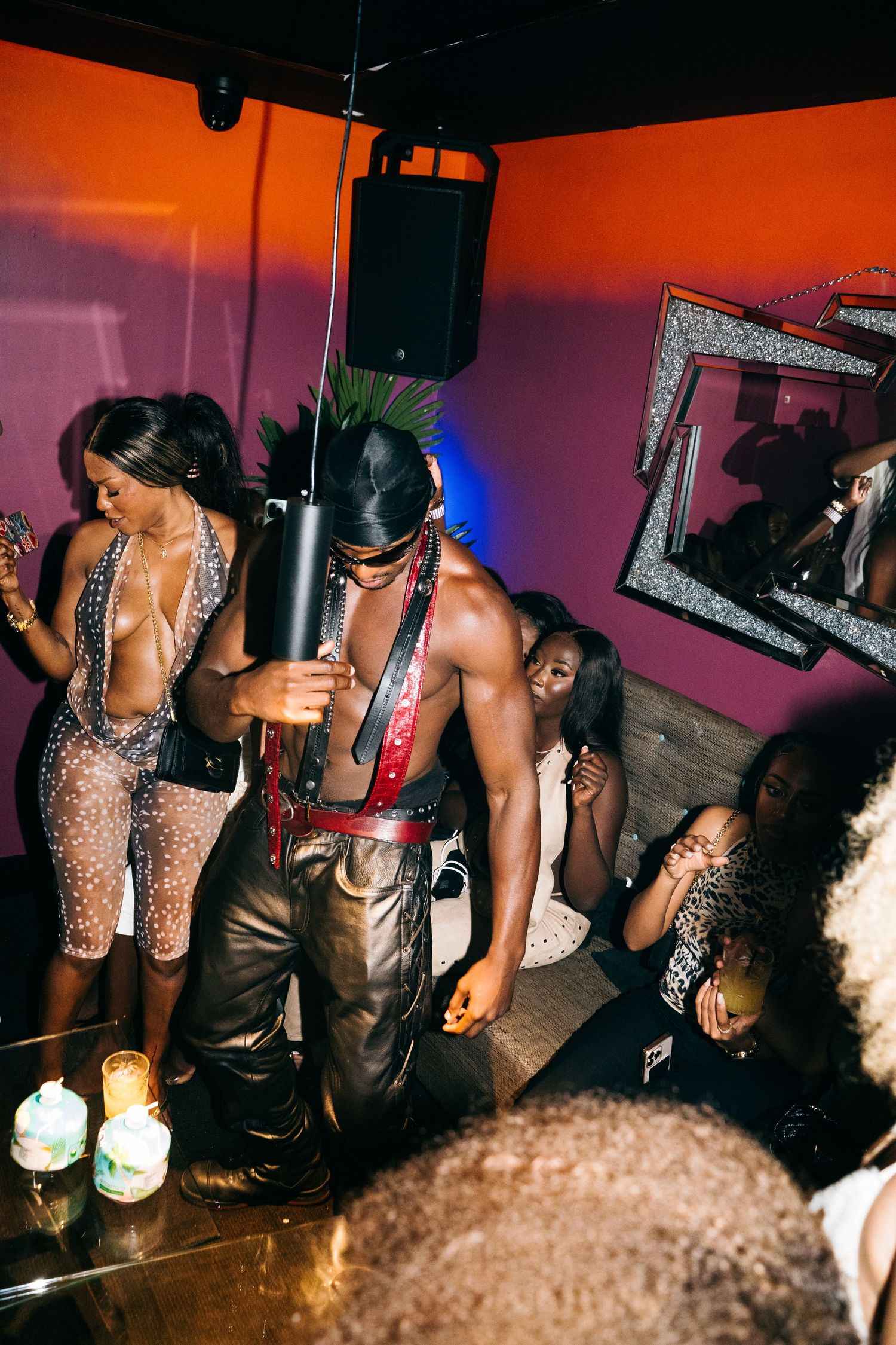 People dancing and socializing at a nightclub with pink walls and blue lighting during an energetic party.