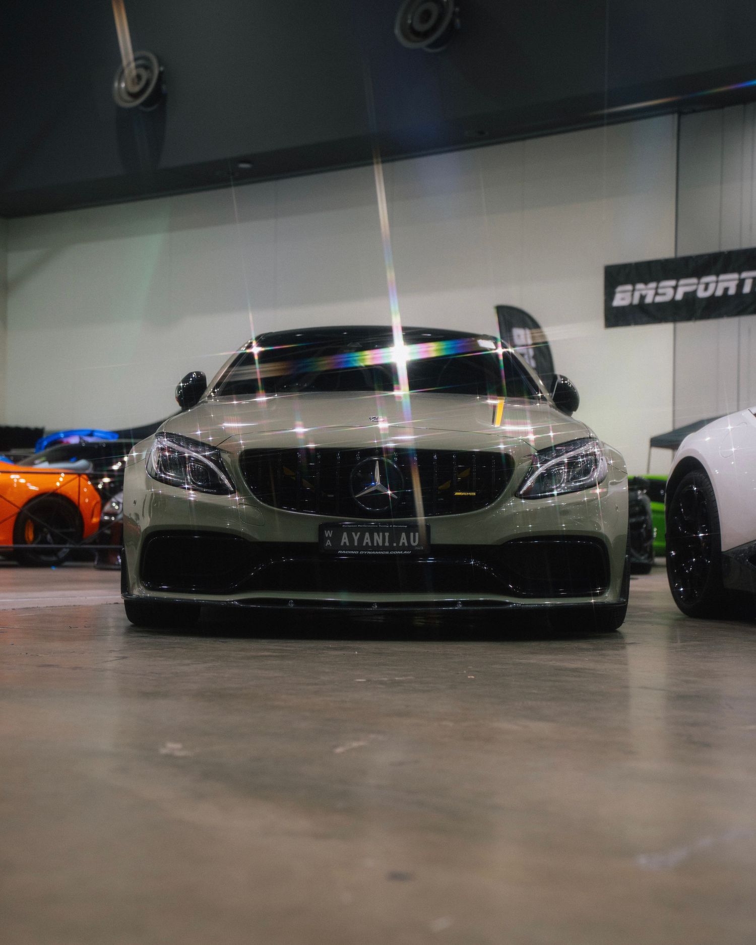 Modified matte green Mercedes-Benz sports car with custom bodywork displayed in a showroom.