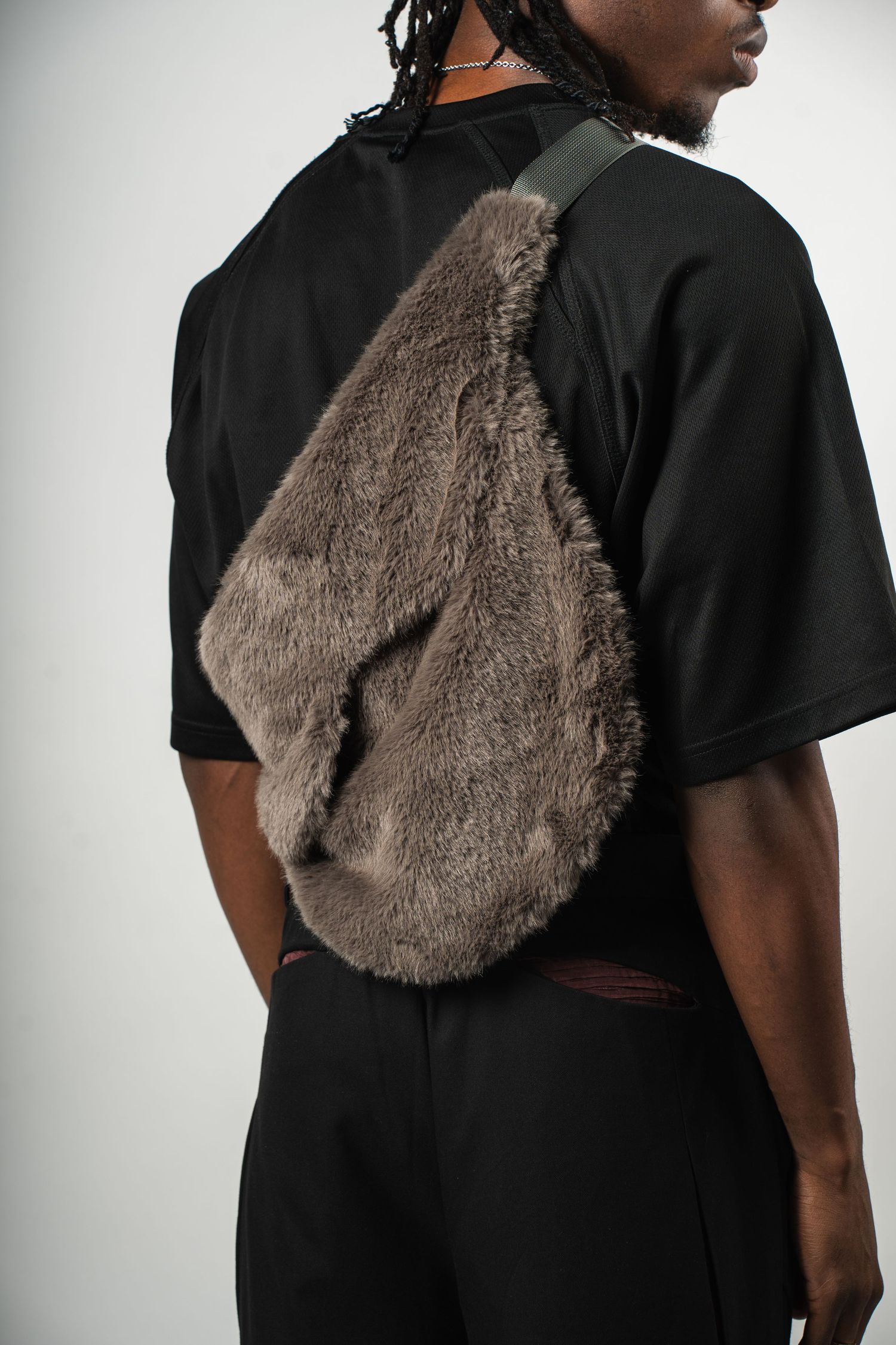 Person wearing black shirt with brown furry crossbody bag.