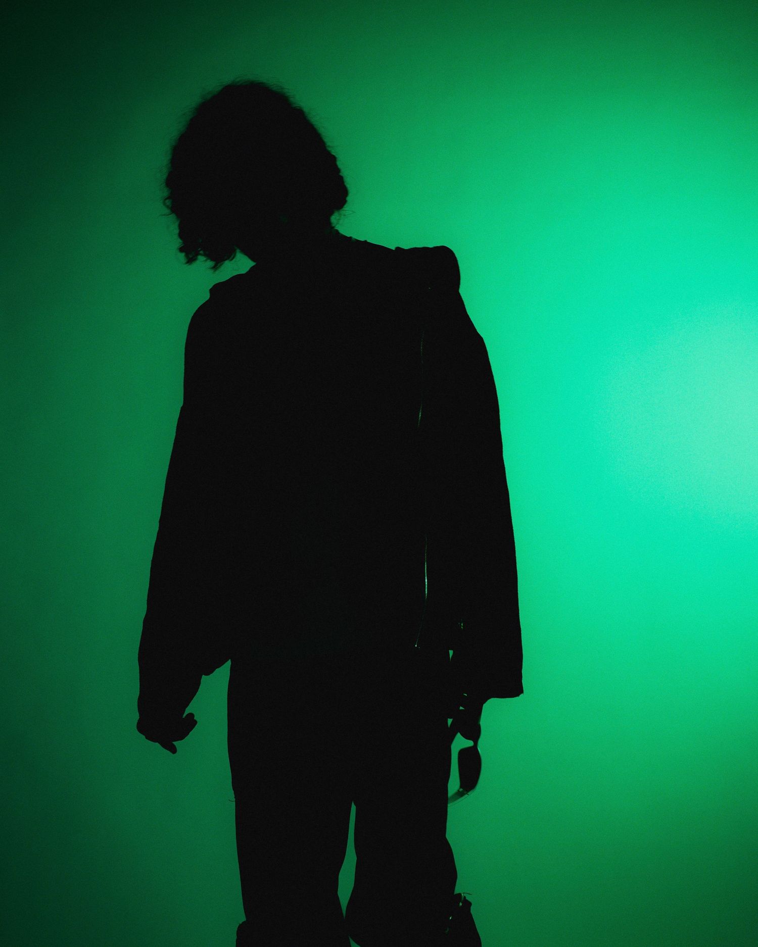 Silhouette of person against vibrant green background creating dramatic contrast.