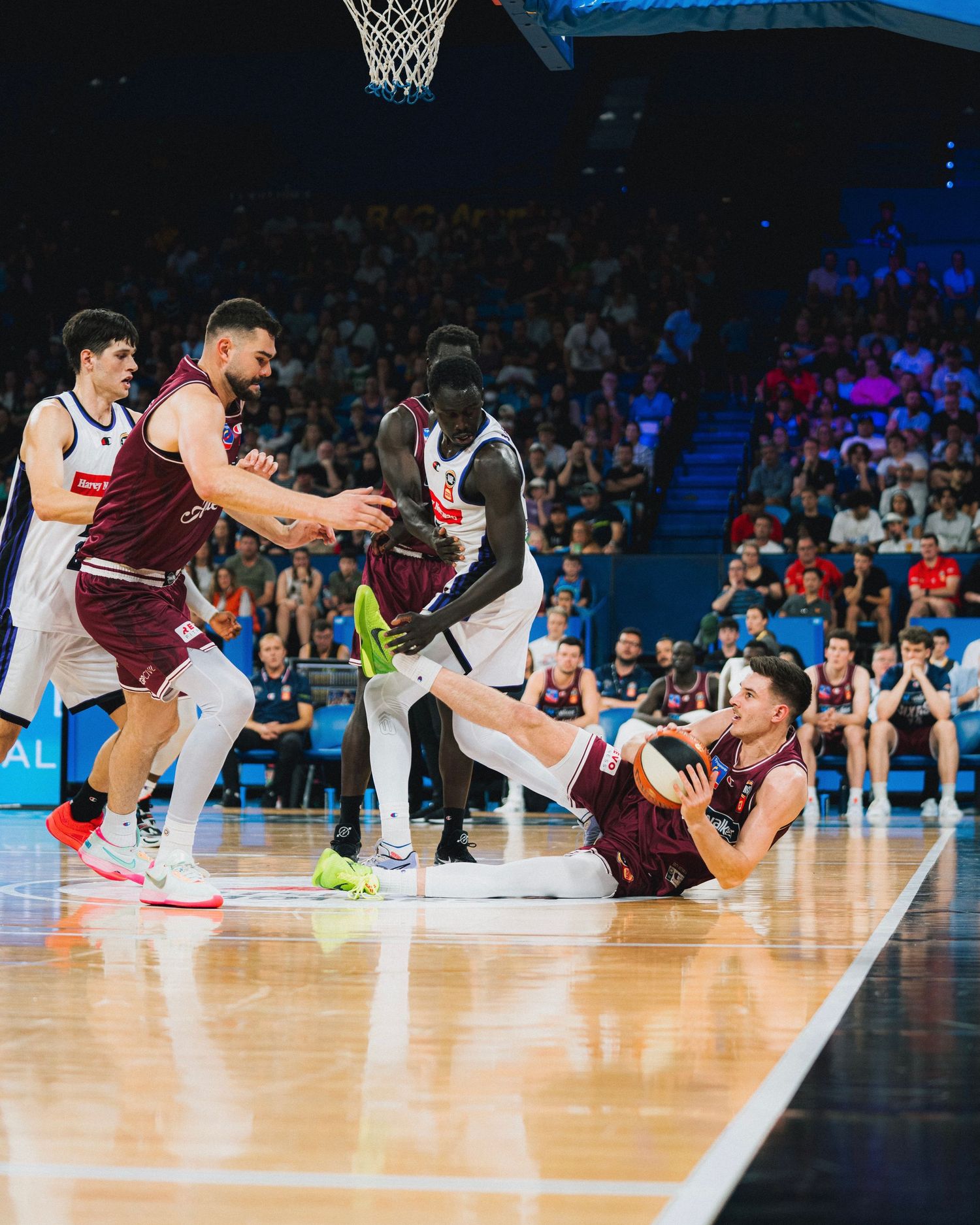 Basketball players scrambling for loose ball during intense game action.