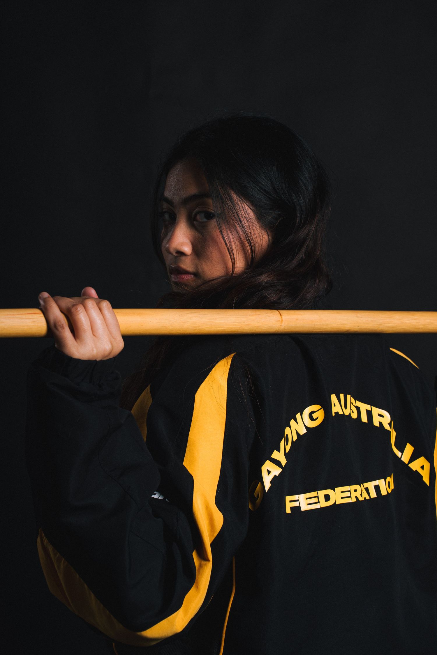 Athletic wear fashion shot featuring black and yellow jacket with text.