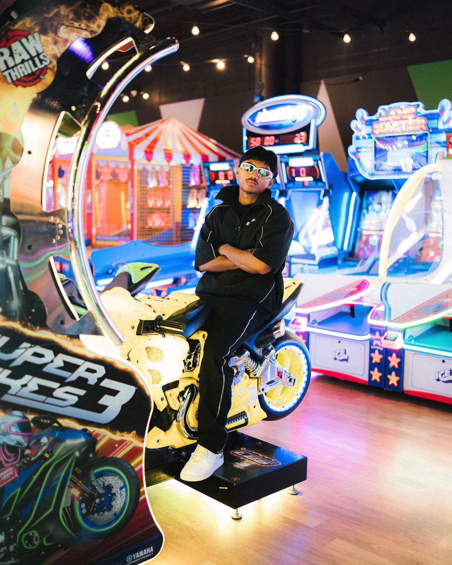 Colorful arcade gaming setup with racing games, neon lights and gaming machines in an indoor entertainment area.