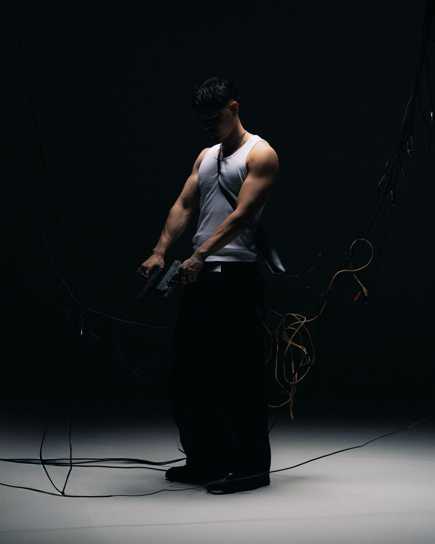 A figure in white tank top and dark pants performs jump rope exercises against a dark background in a dramatic series.