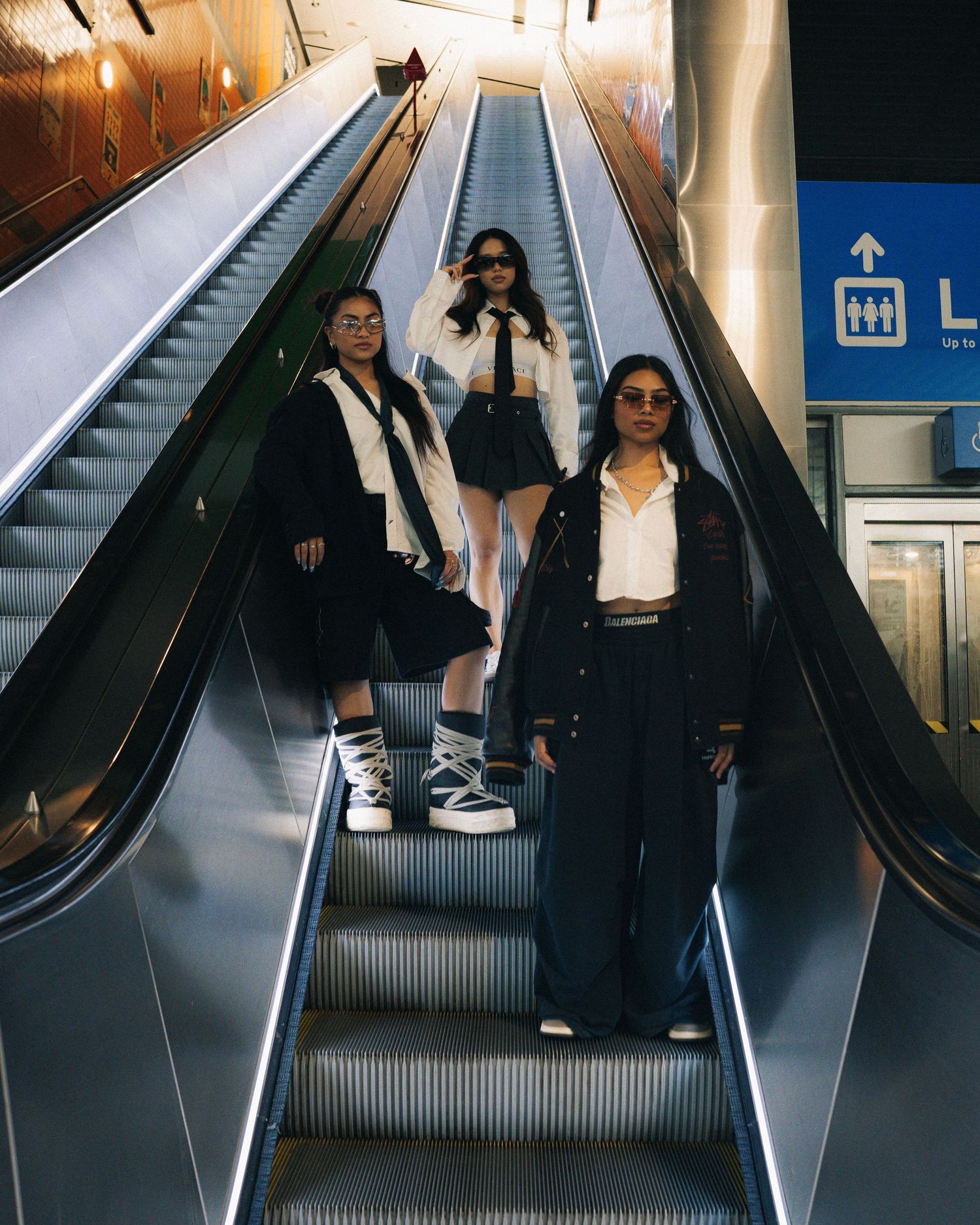 People ascending escalator in modern transit station with bright lighting.