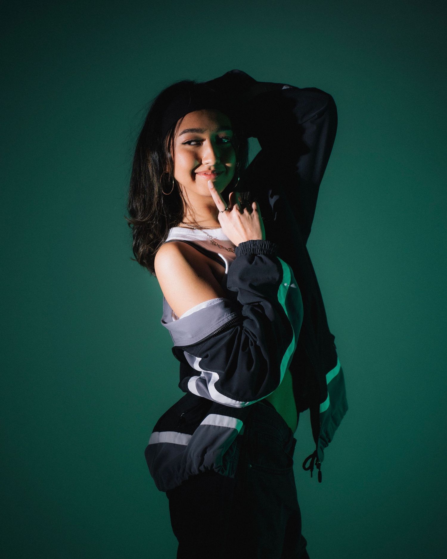 Stylish portrait against green backdrop featuring person in black and white athletic wear.