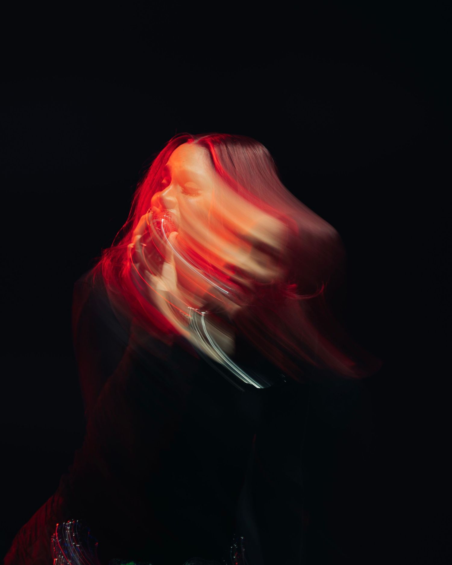Abstract motion blur photography of red and pink flowing movement against dark background creates ethereal effect.