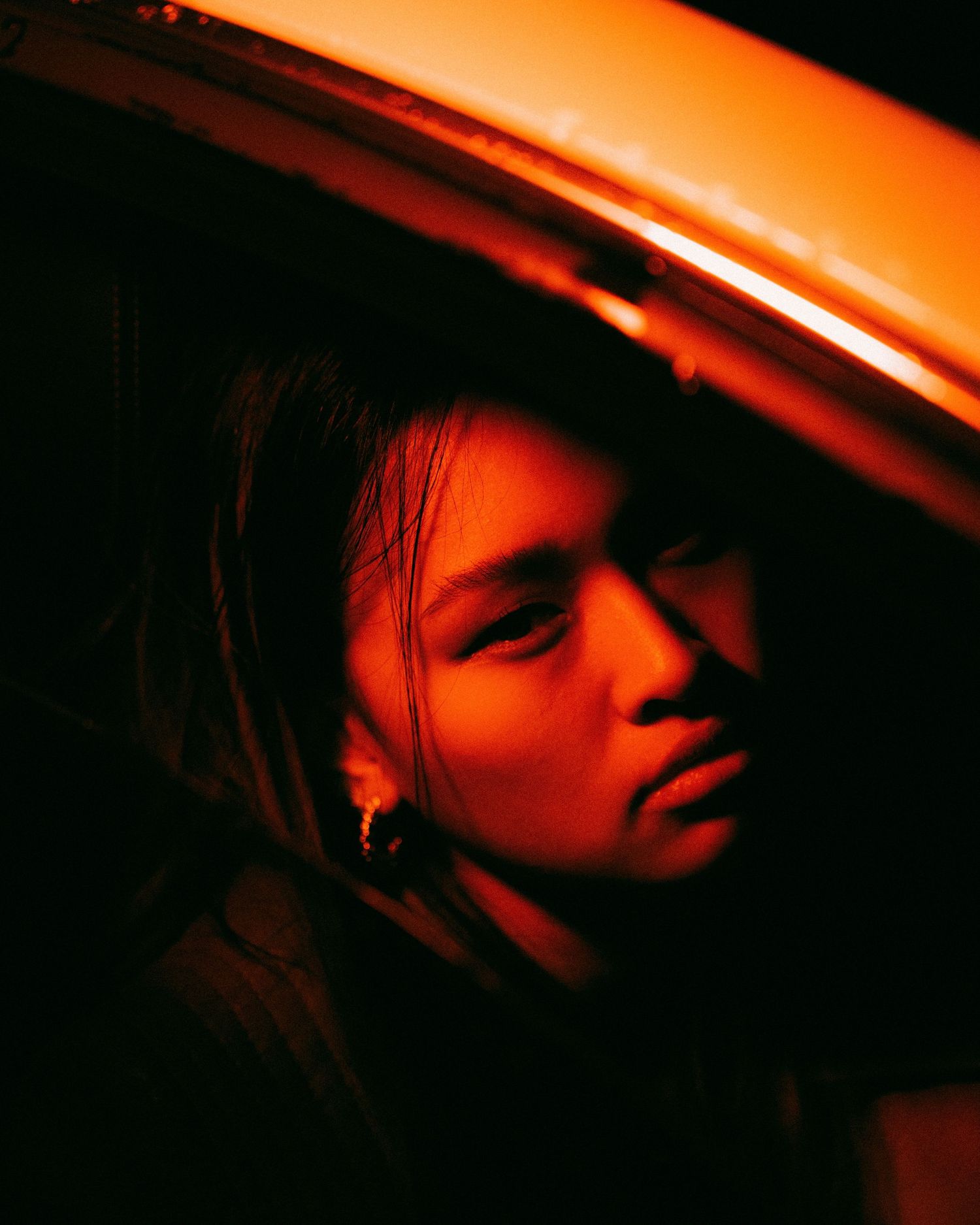 Artistic portrait bathed in warm orange lighting creating a moody atmospheric effect.