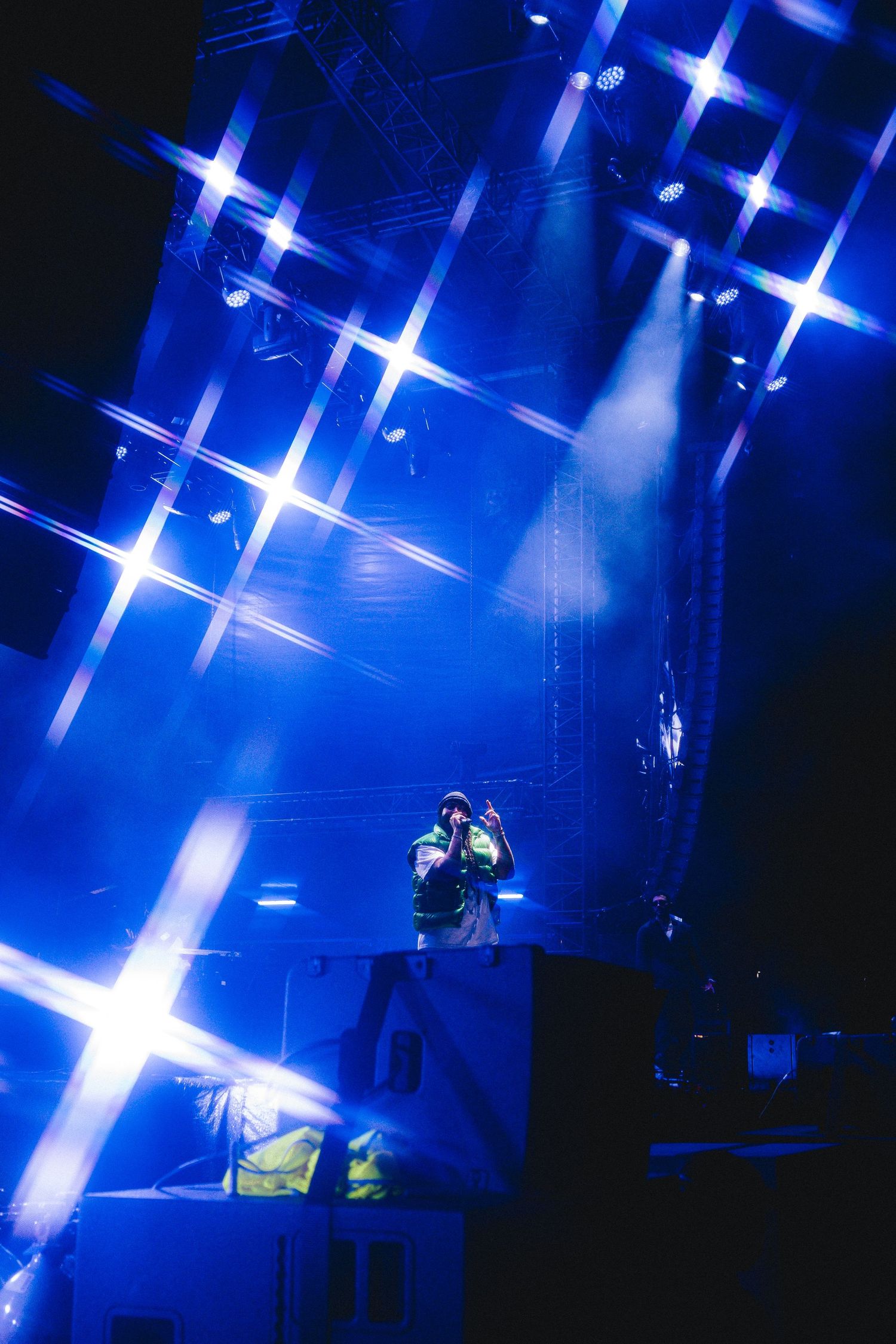 Concert stage illuminated with bright blue spotlights creating dramatic star-like patterns during a performance.