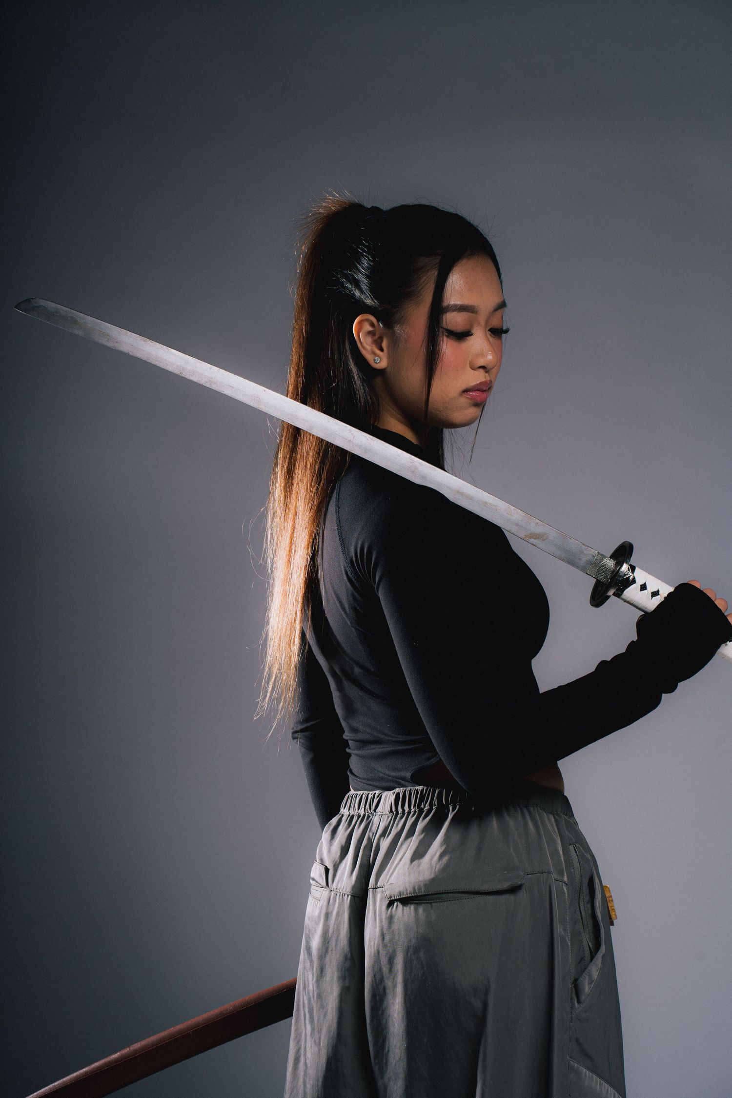 Person in black attire holding a katana sword poses dramatically against a dark background in a sequence of photos.