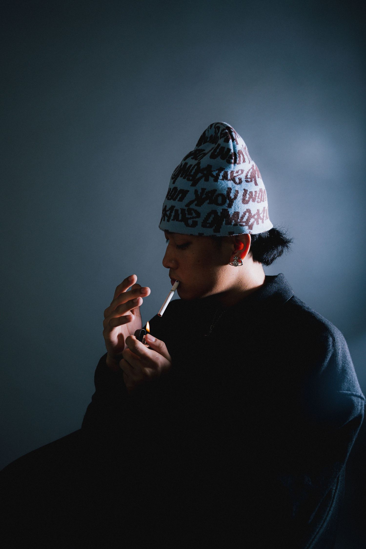 A dark silhouette wearing a white beanie is shown in a dramatic side profile against a moody blue-gray background.