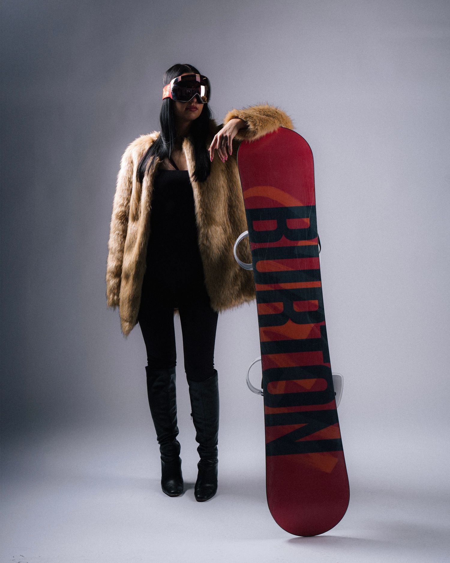 Three views of a person wearing black pants and holding a large red and navy striped skateboard or deck against a gray background.