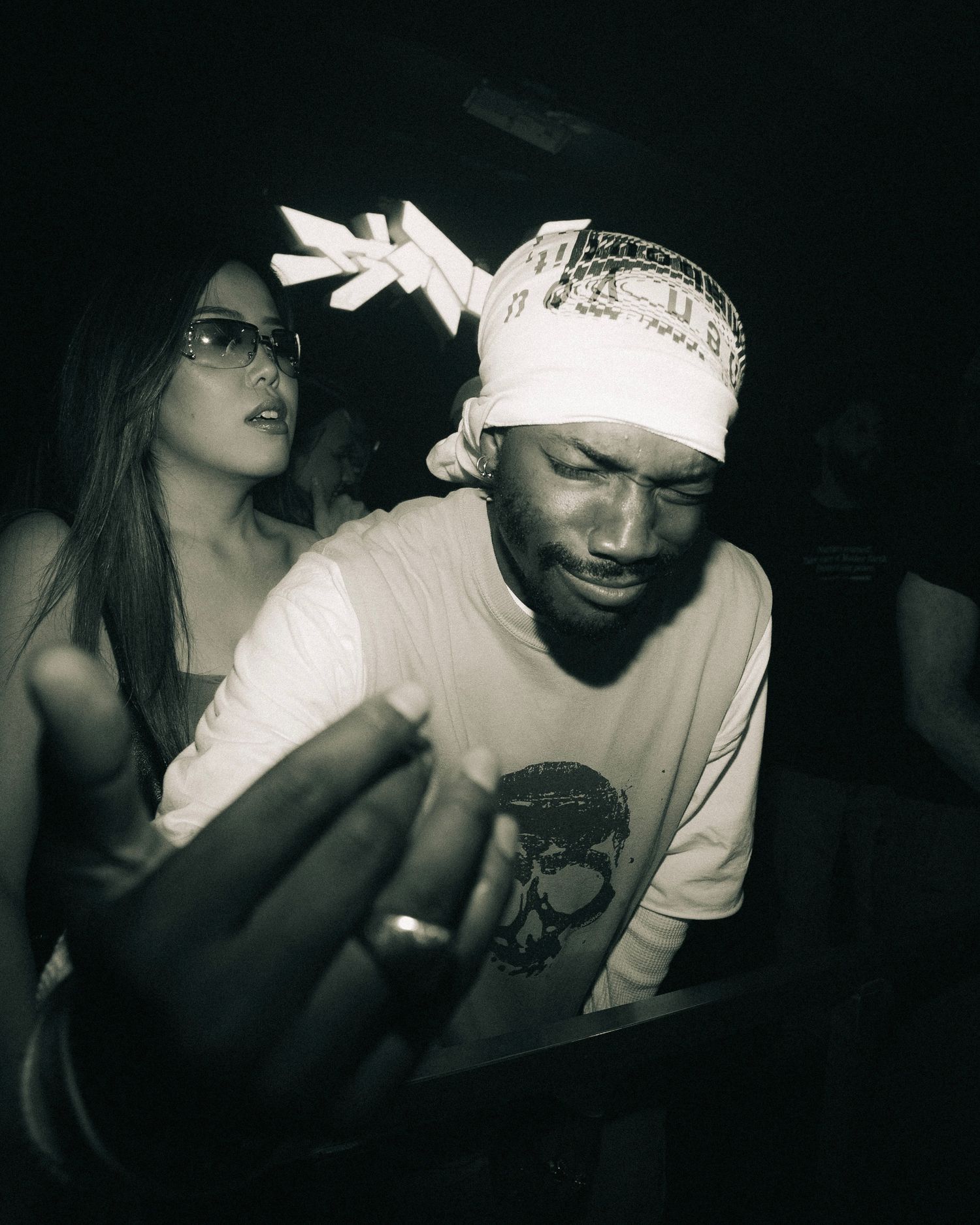 Partygoer wearing white shirt and bandana enjoying music at a nightclub.