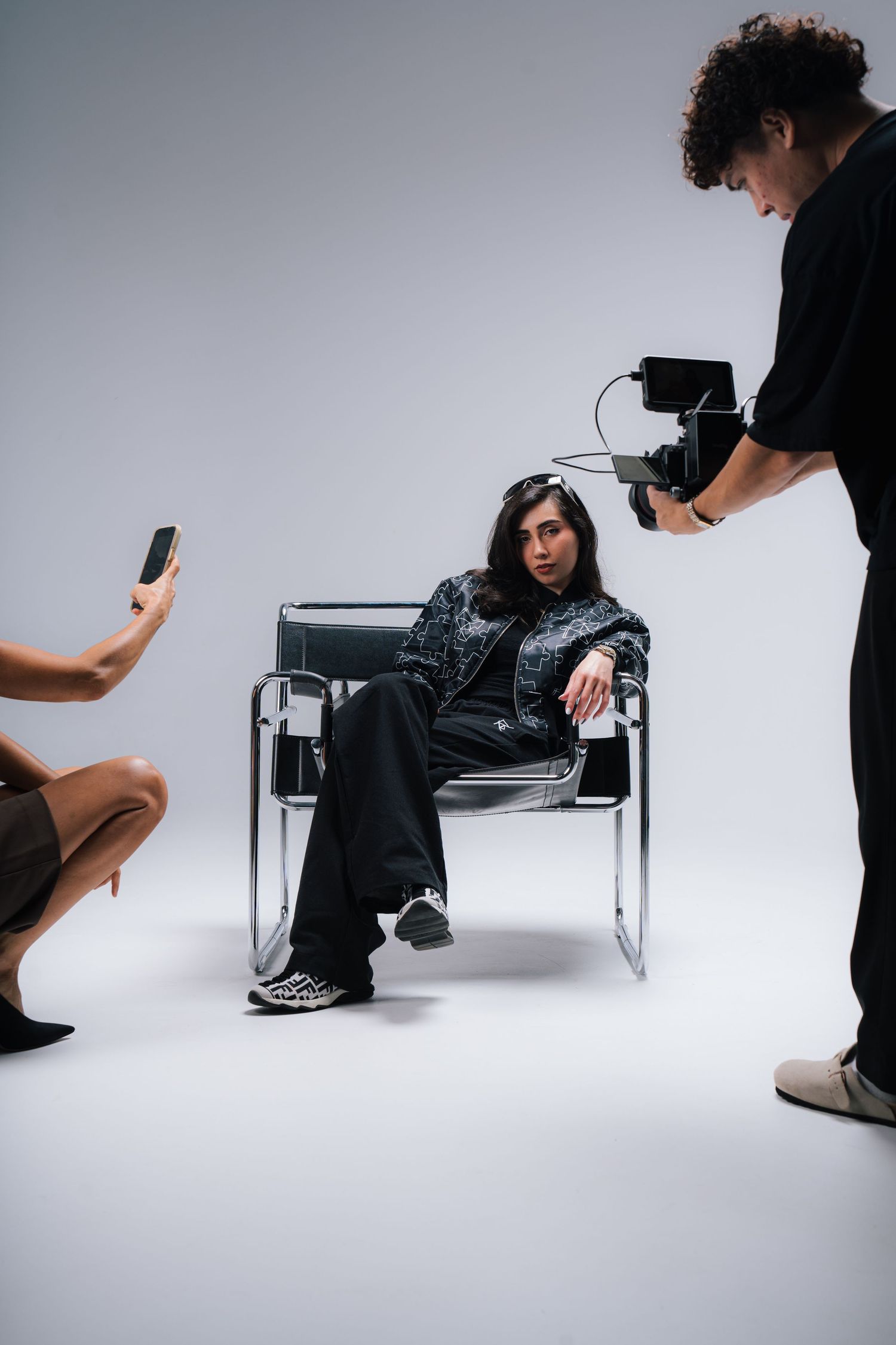 Behind-the-scenes photo shoot with model, photographer, and assistant in studio.