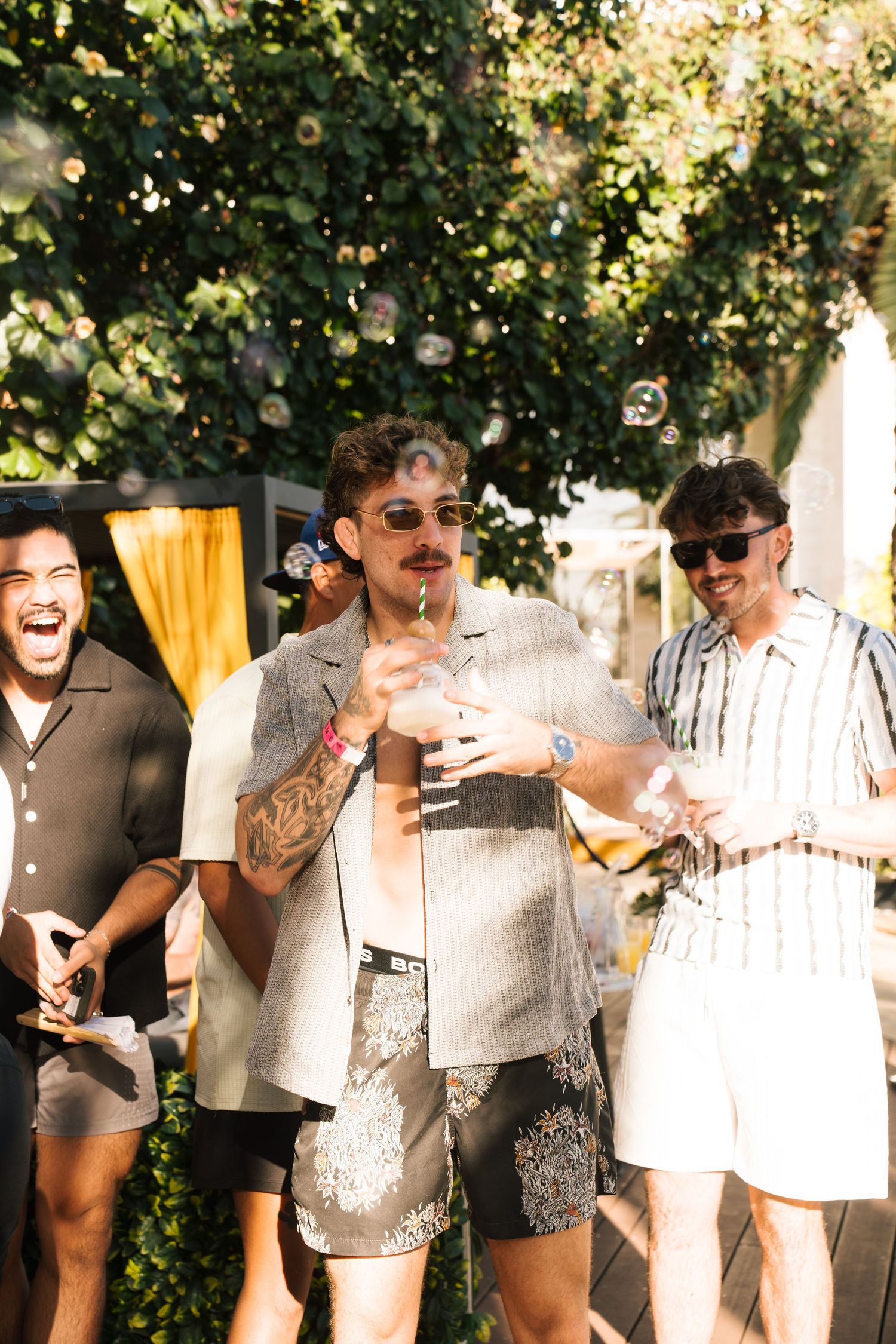 Friends enjoying drinks and bubbles at an outdoor summer party in casual attire.