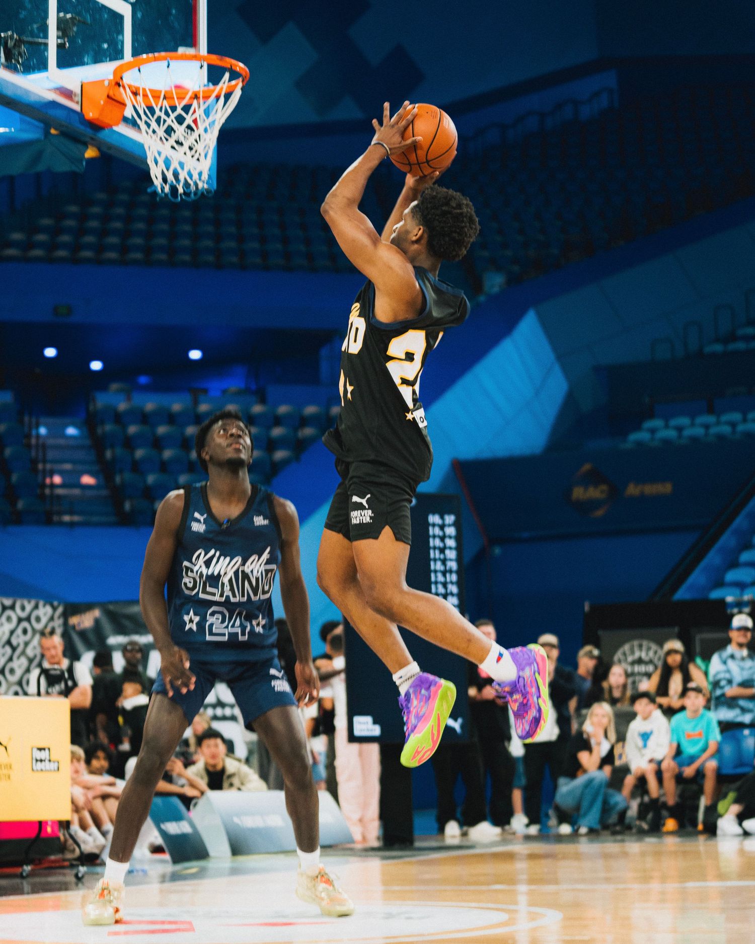Player leaps high for a jump shot during an indoor basketball game.