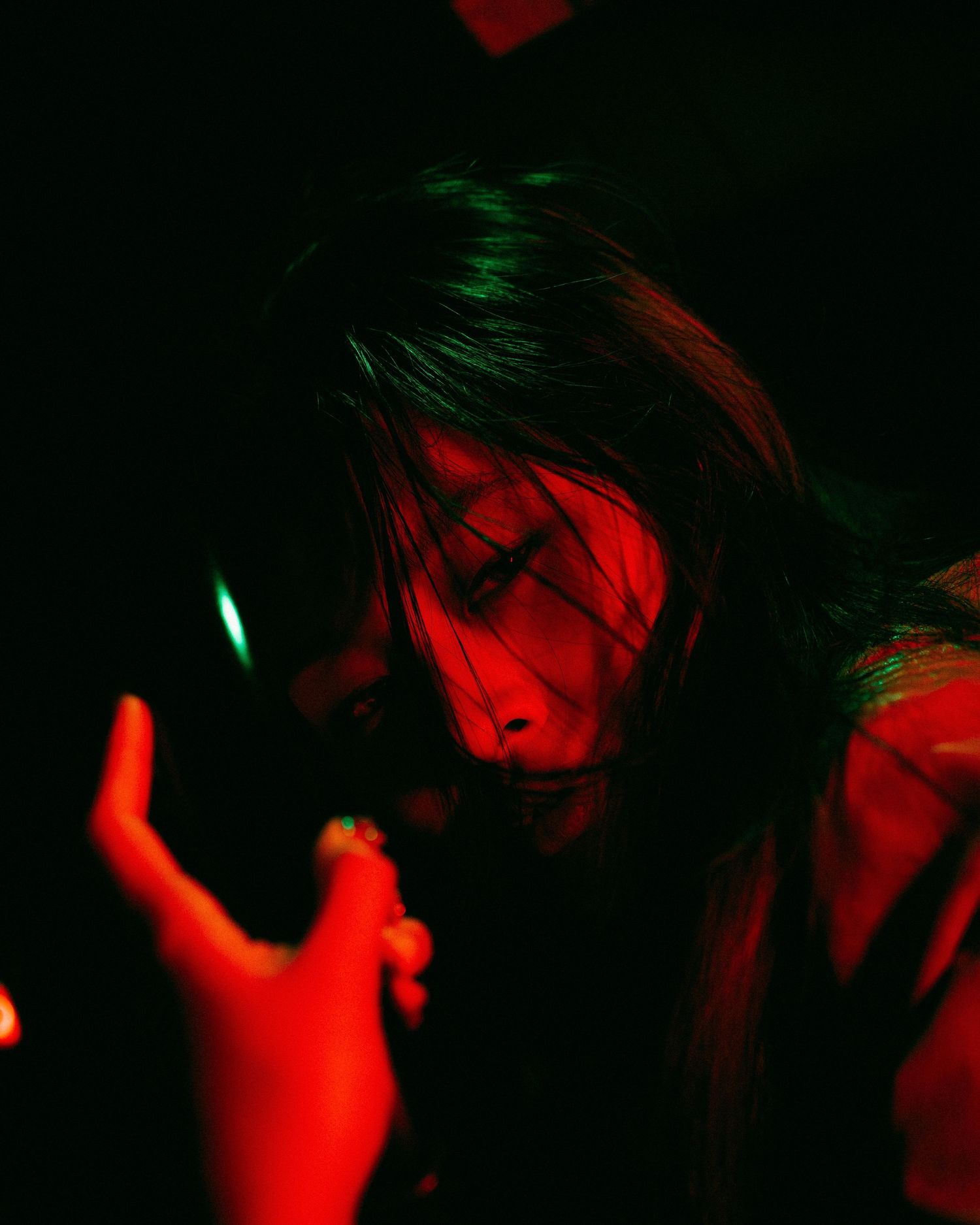 Artistic dark portrait with red and green lighting creating a moody atmosphere in low-key photography style.
