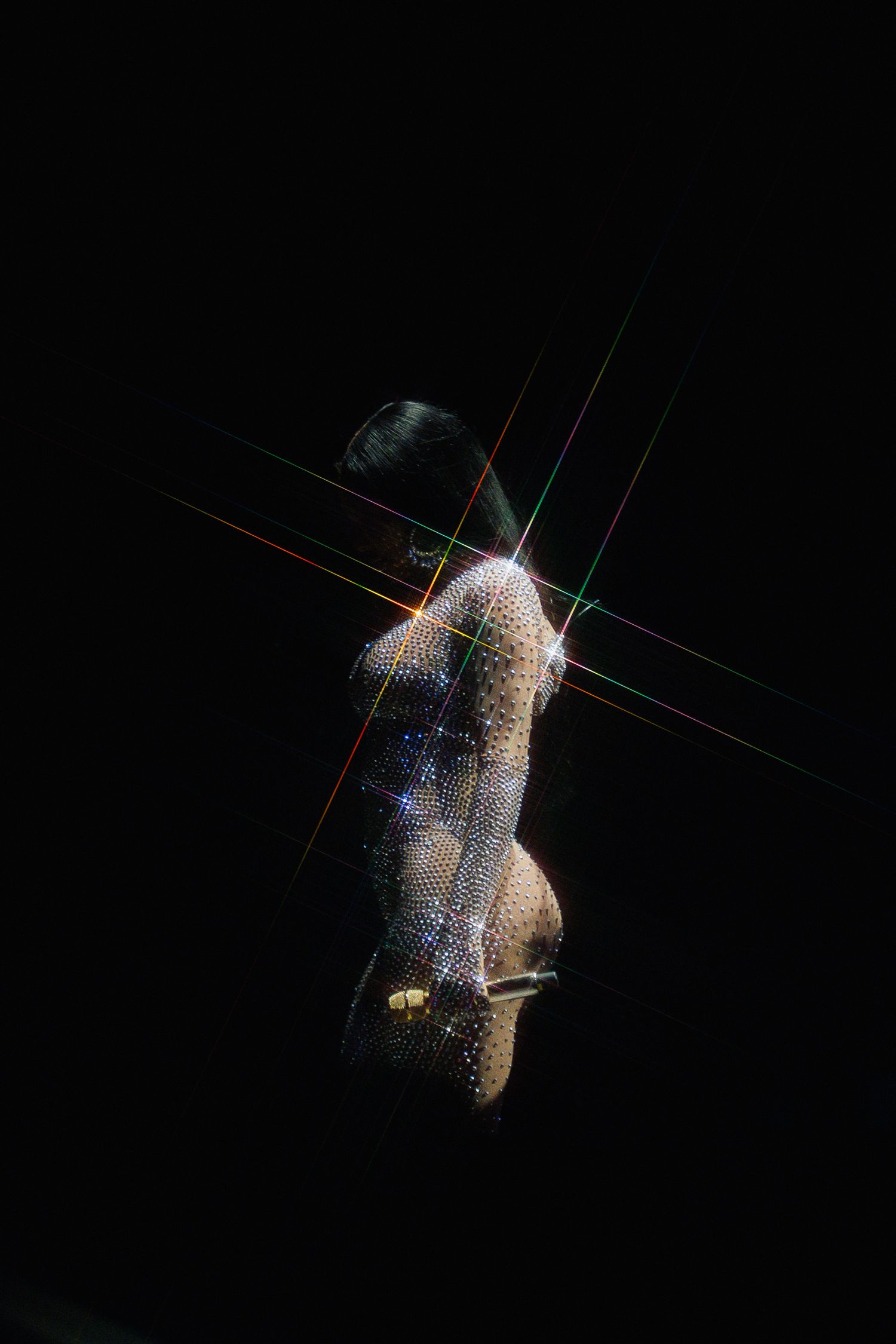 Illuminated crystalline droplet suspended in darkness with glowing light refractions creating a sparkling effect.