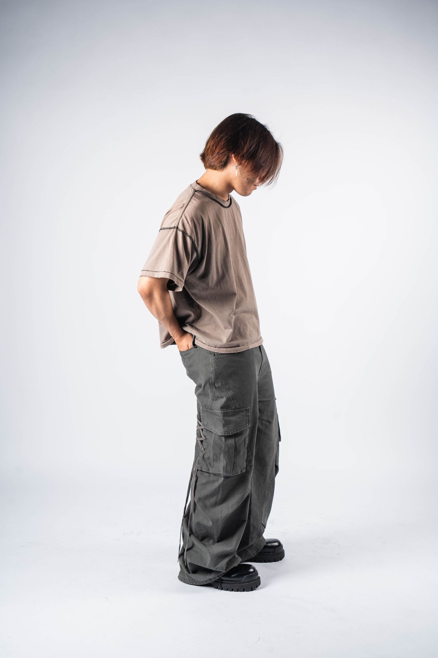 Side view of grey cargo pants styled with beige t-shirt against white background.