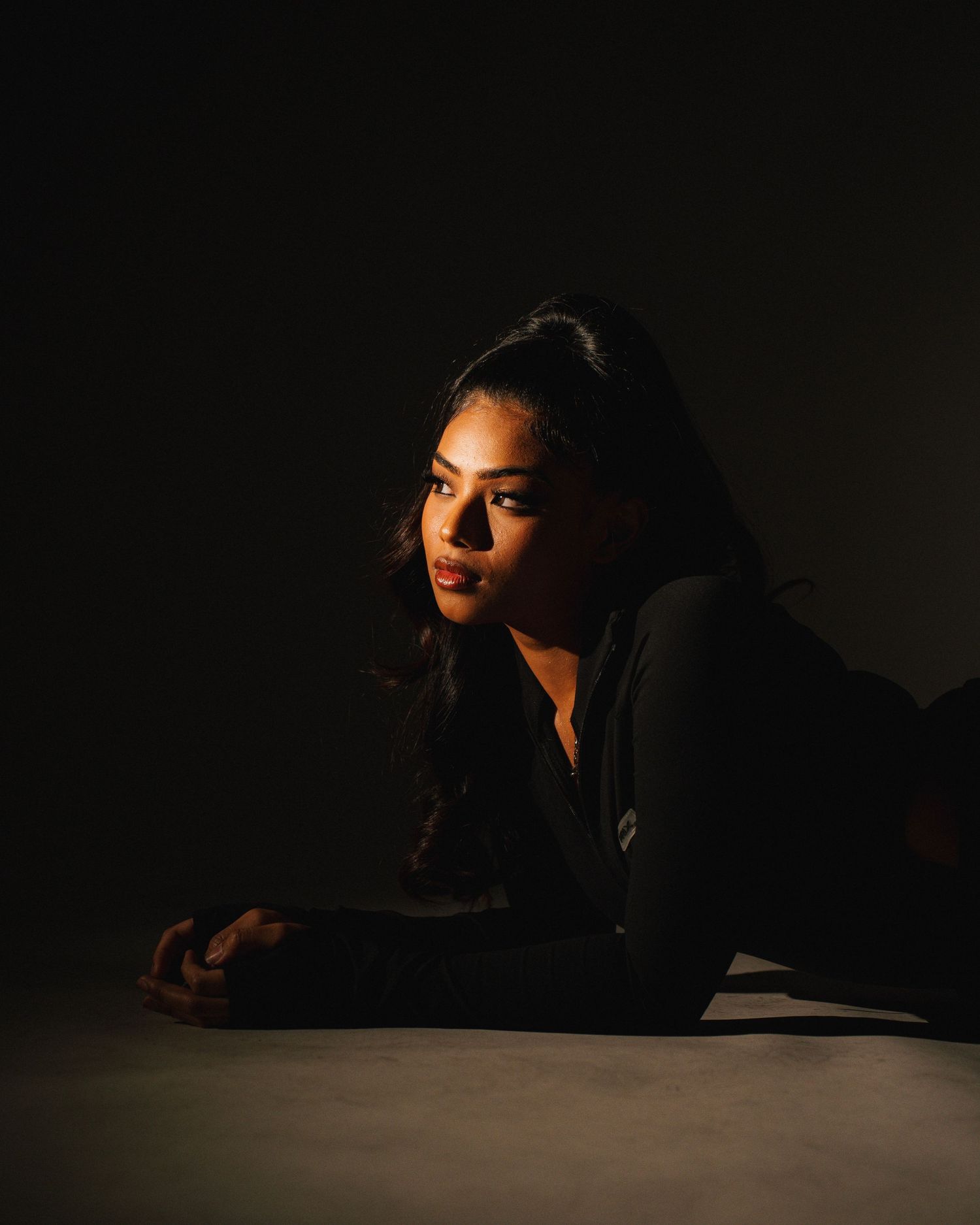 Low key portrait of person lying down with dramatic side lighting.