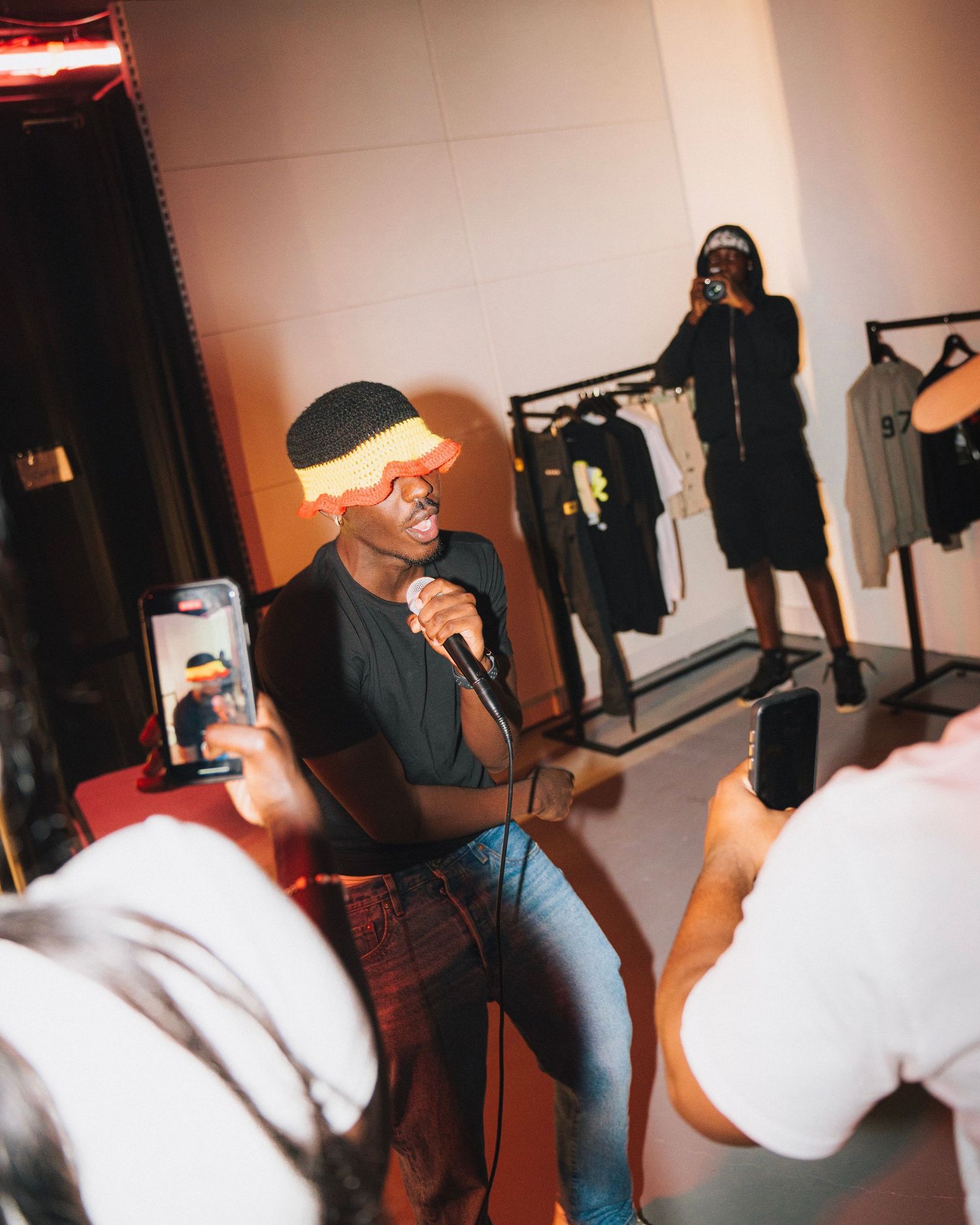 Performance inside a clothing store with someone singing while another person records on their phone.