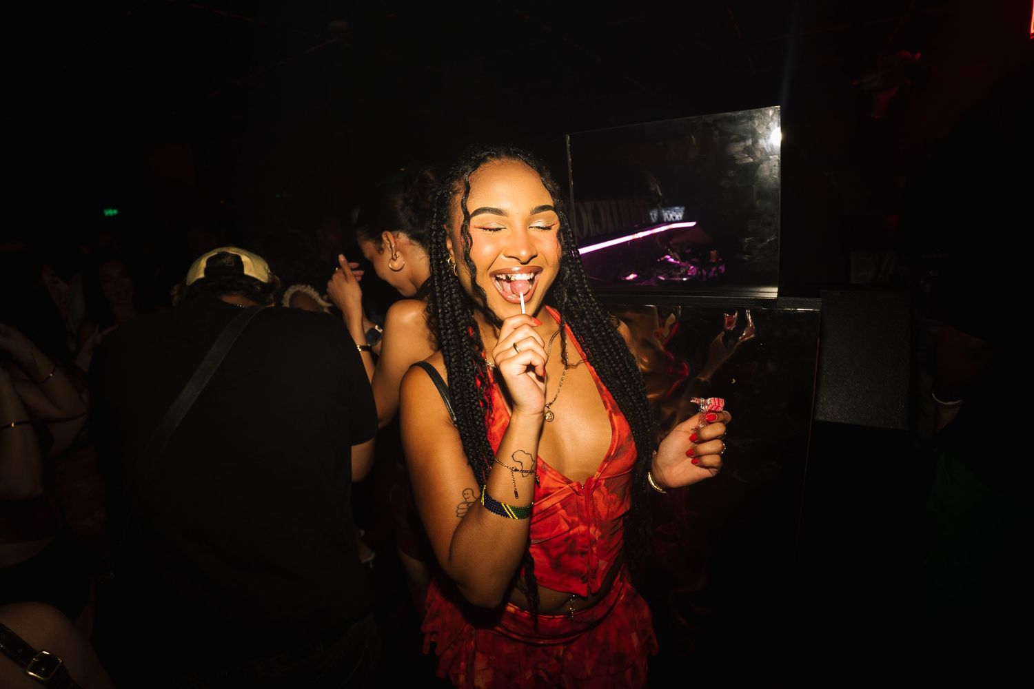 People dancing and enjoying themselves in a dimly lit nightclub atmosphere with colorful lighting effects.