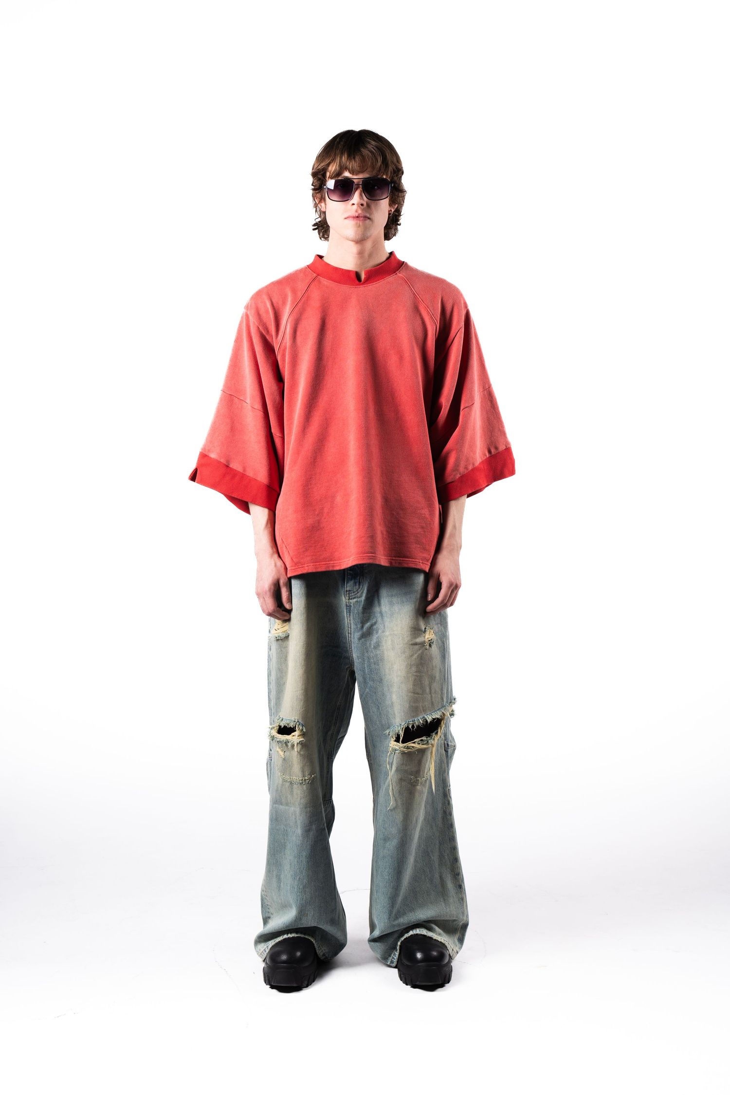 Oversized red sweater paired with distressed wide-leg jeans against white background.