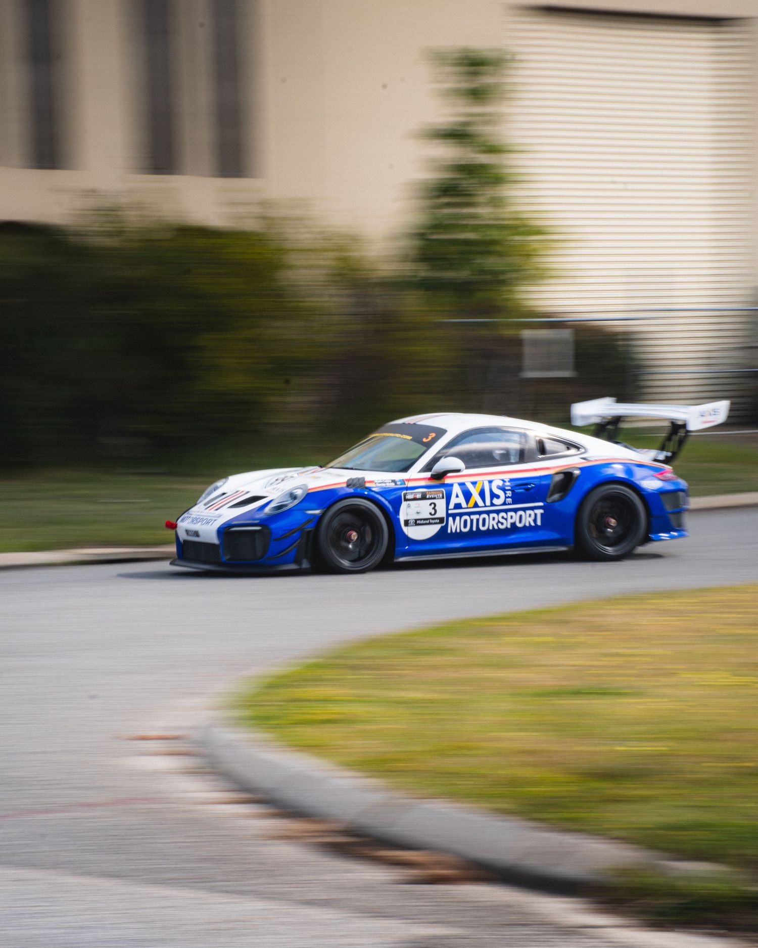 Blue Porsche race car with EXEDY livery captured in motion on track.