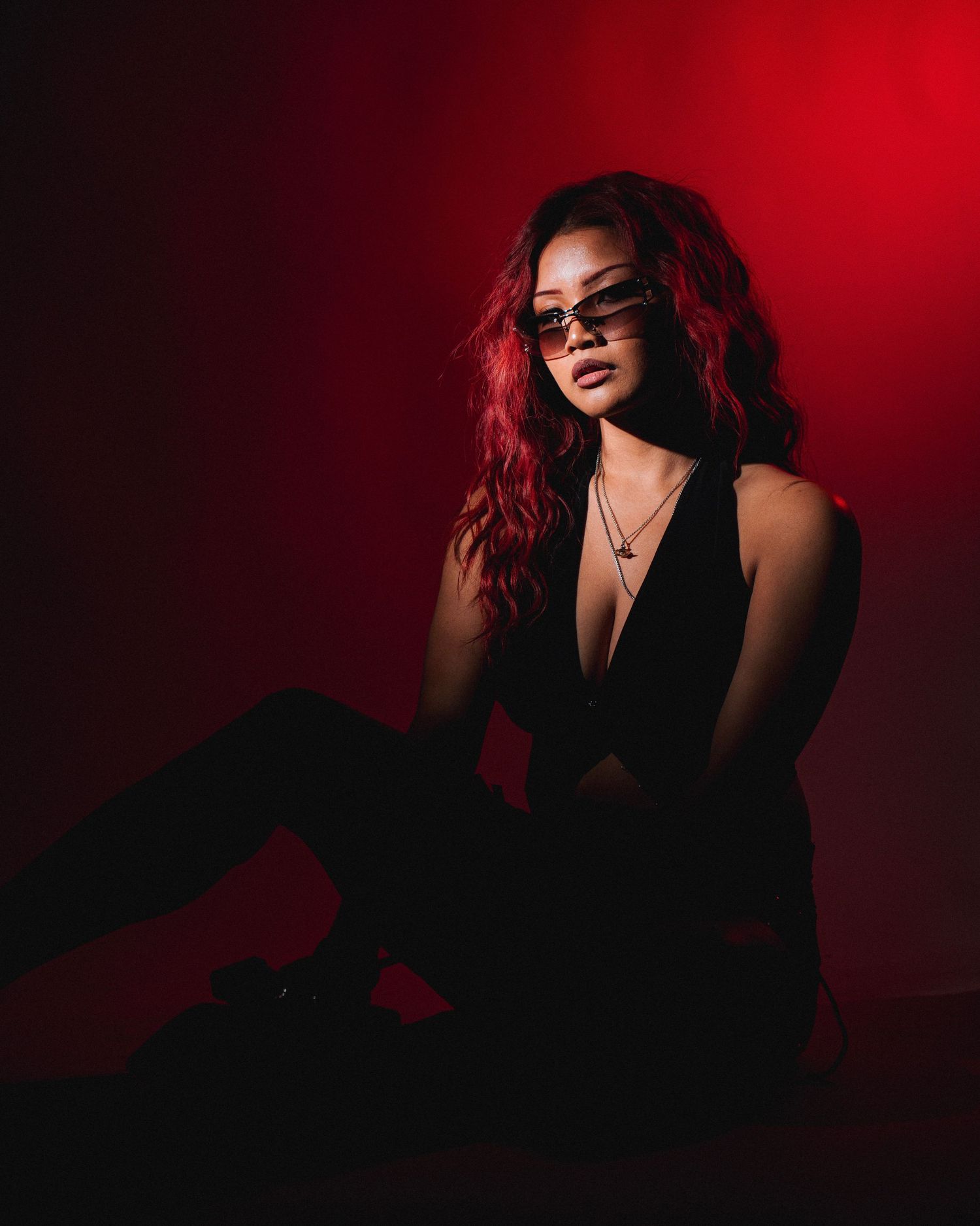 Dramatic fashion portraits against deep red background showing silhouette and moody lighting effects.
