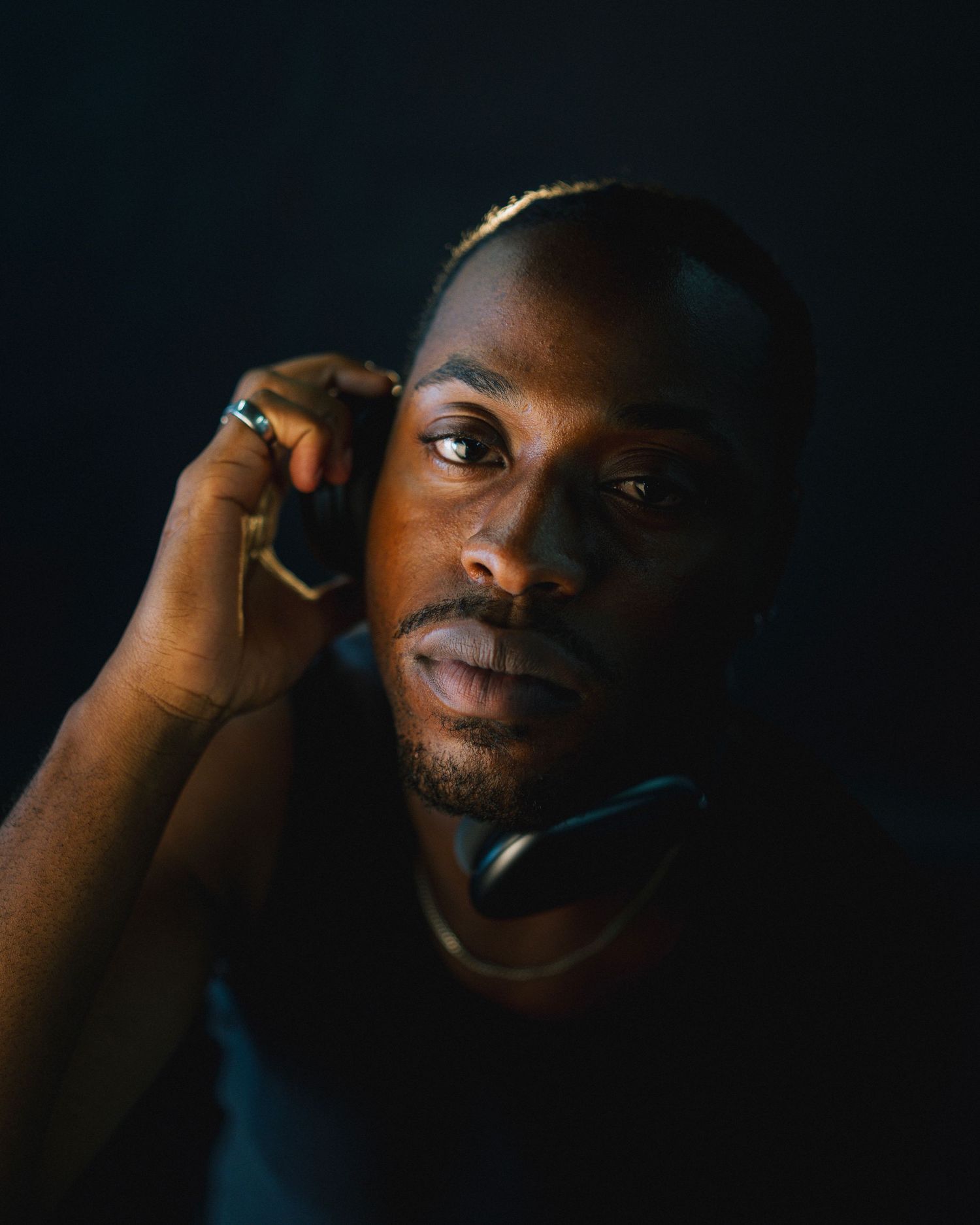 Close up portrait of man in dramatic low key lighting with hand near face.