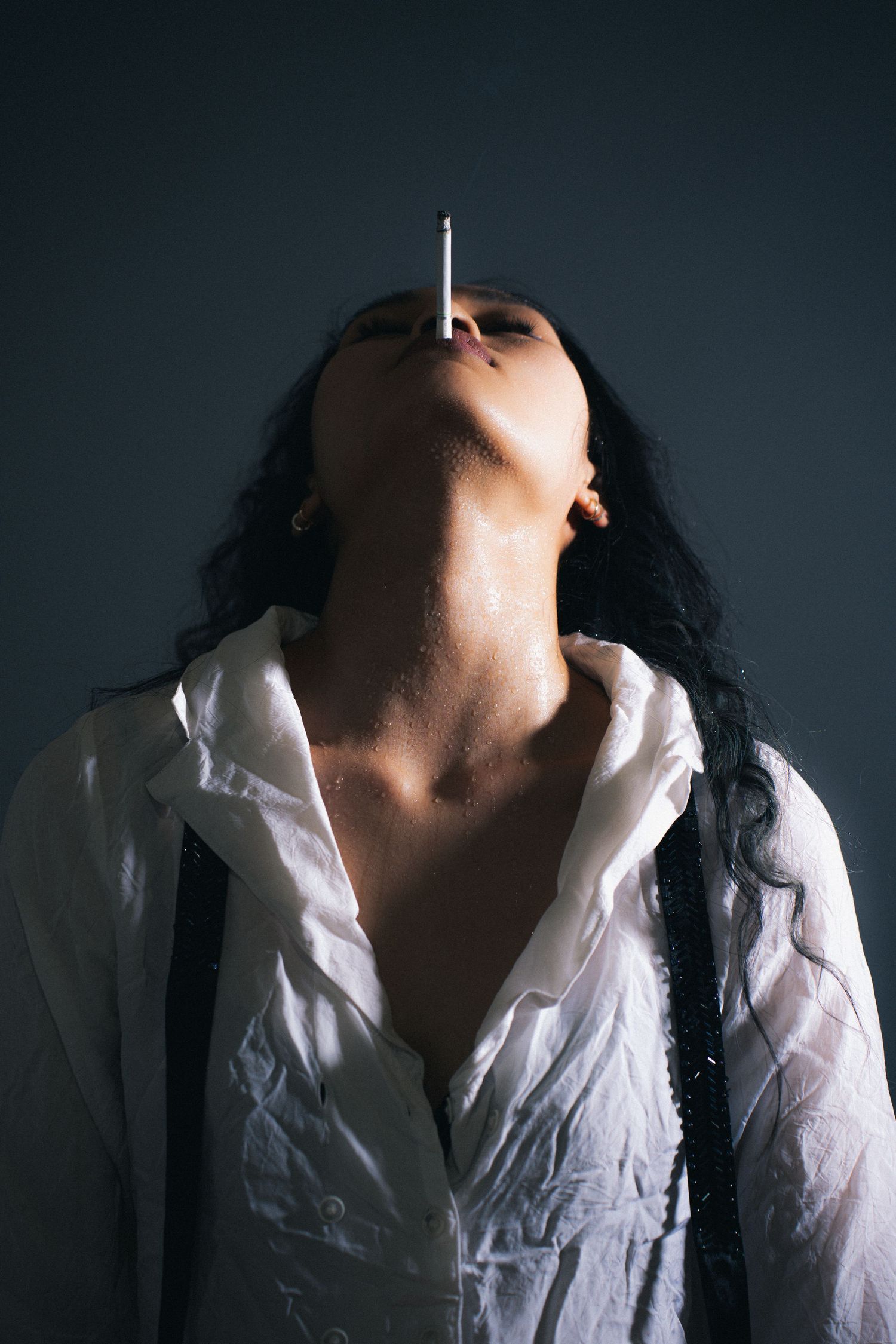 A dramatic series of silhouetted photos shows a figure in white shirt leaning back with dark shadows against a stark background.