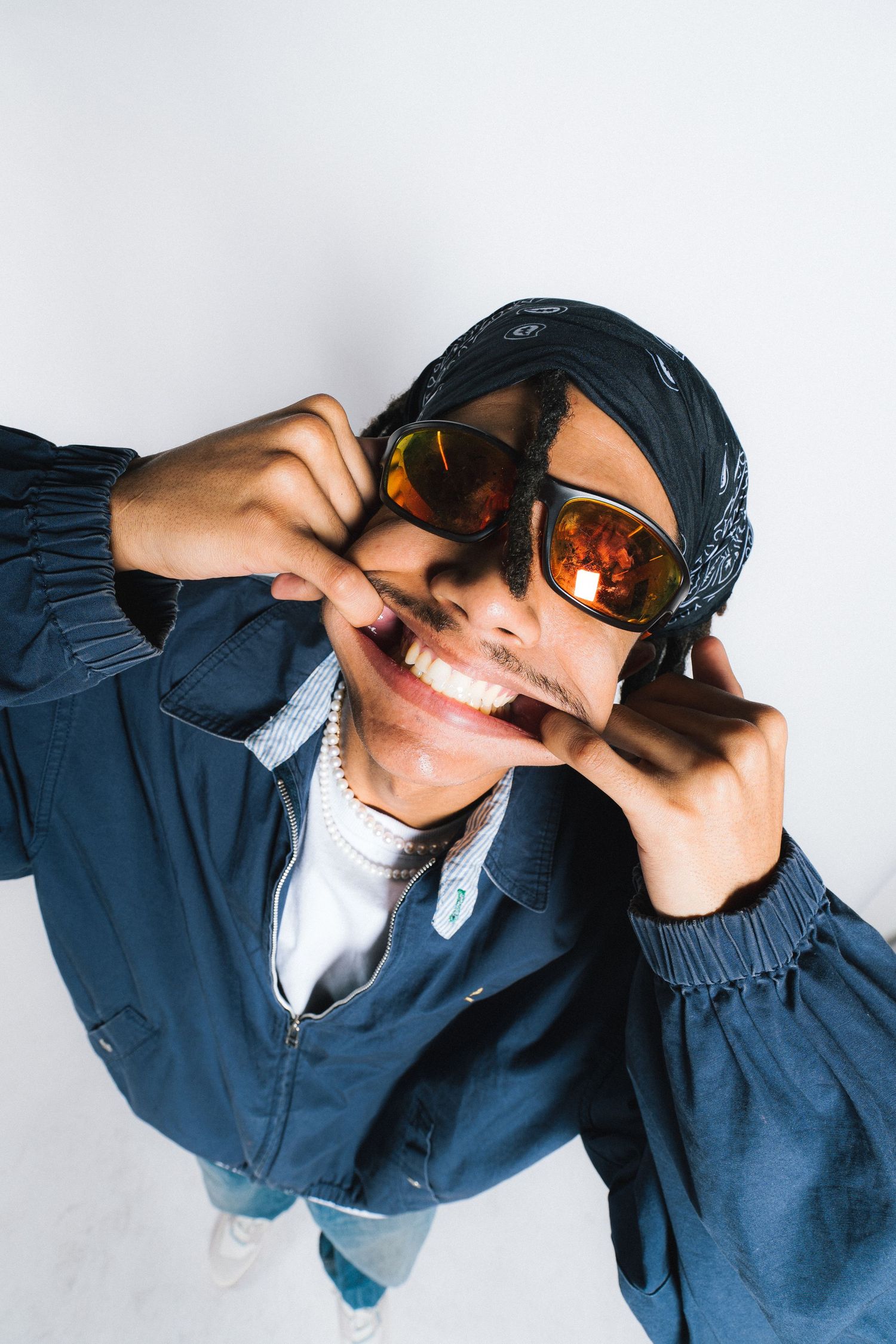 Overhead shot of someone in blue jacket wearing orange sunglasses making a playful expression.