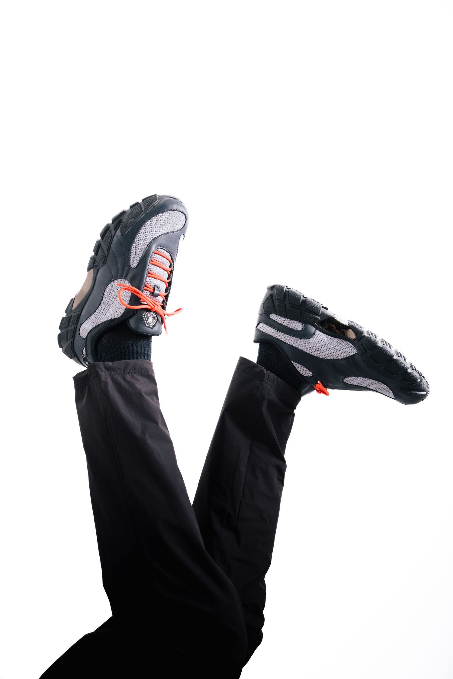 Athletic shoes with orange laces shown in dynamic upside-down pose against white background.