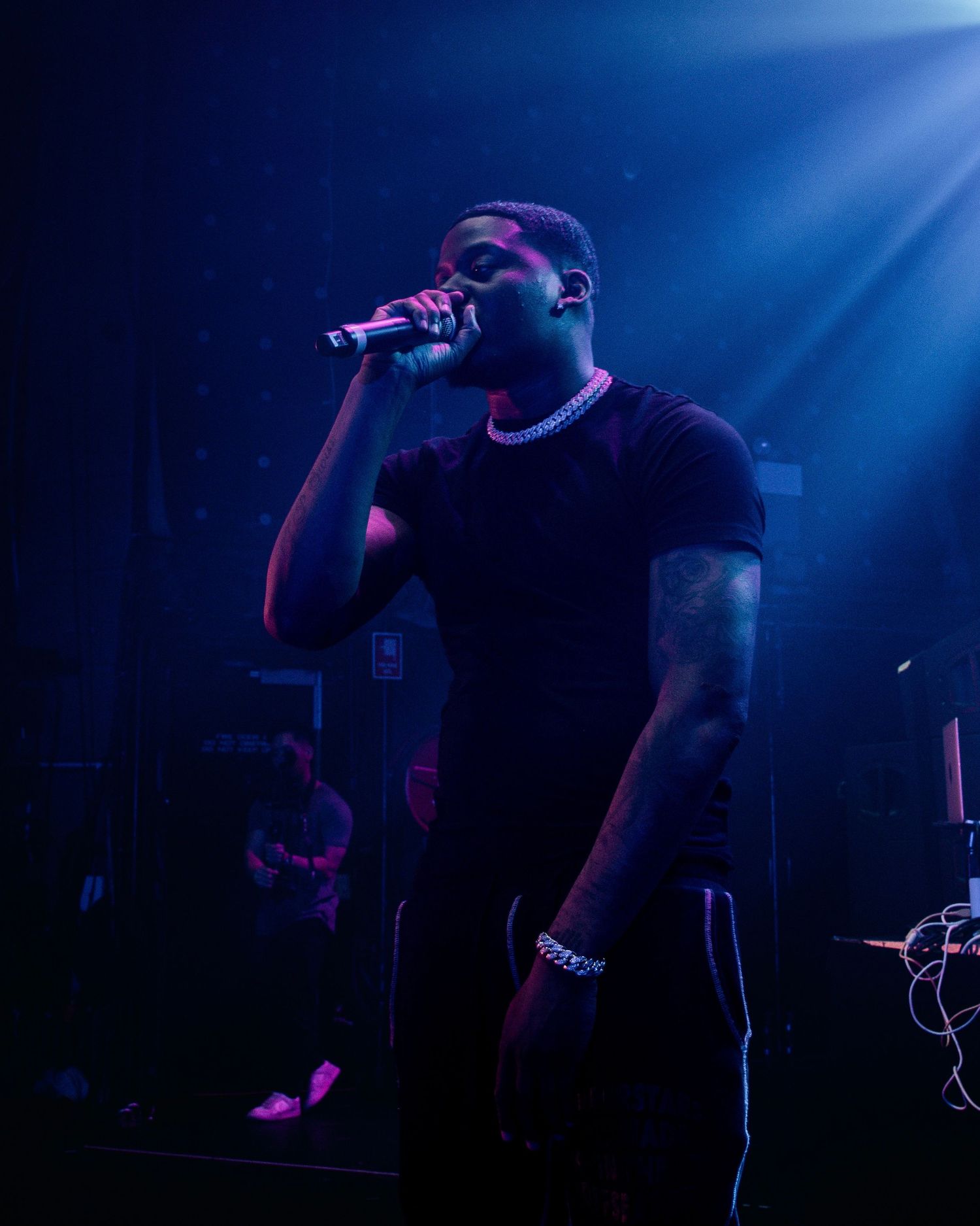 Concert performer singing on stage illuminated by blue lighting effects.