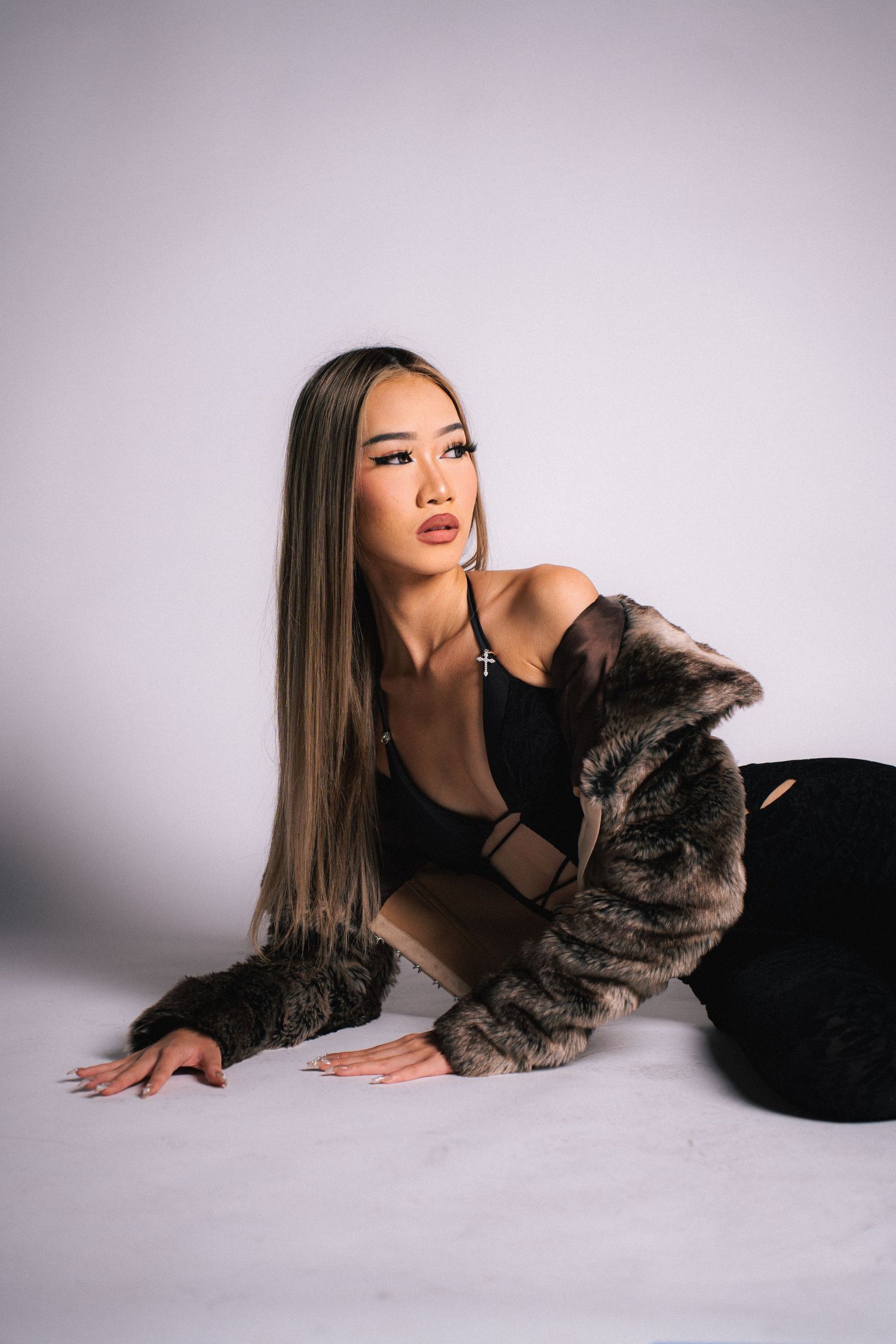 A studio portrait series showing a person in black clothing lying on white backdrop with a gray cat companion.