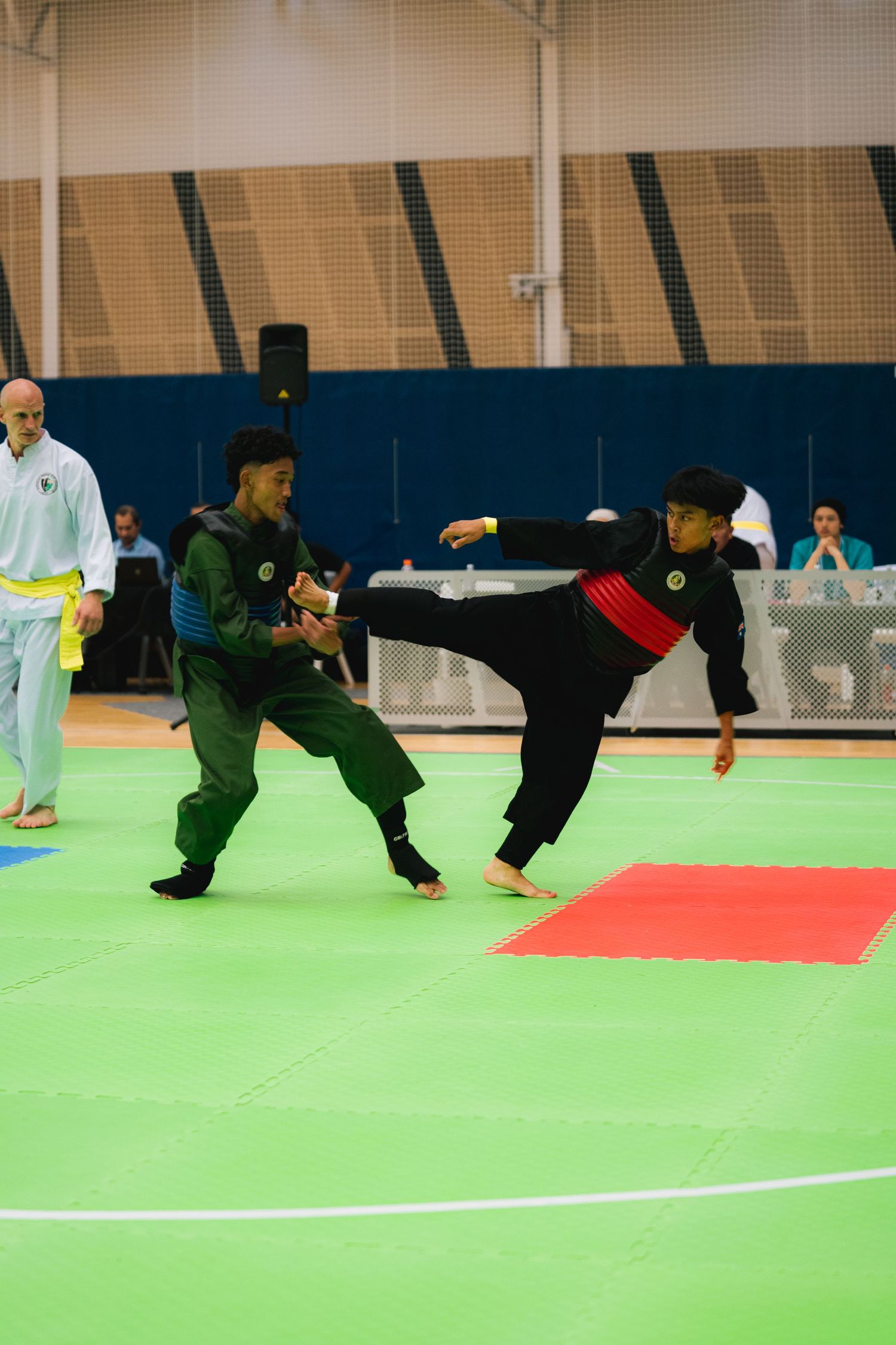 Two competitors demonstrate martial arts techniques during a tournament match.