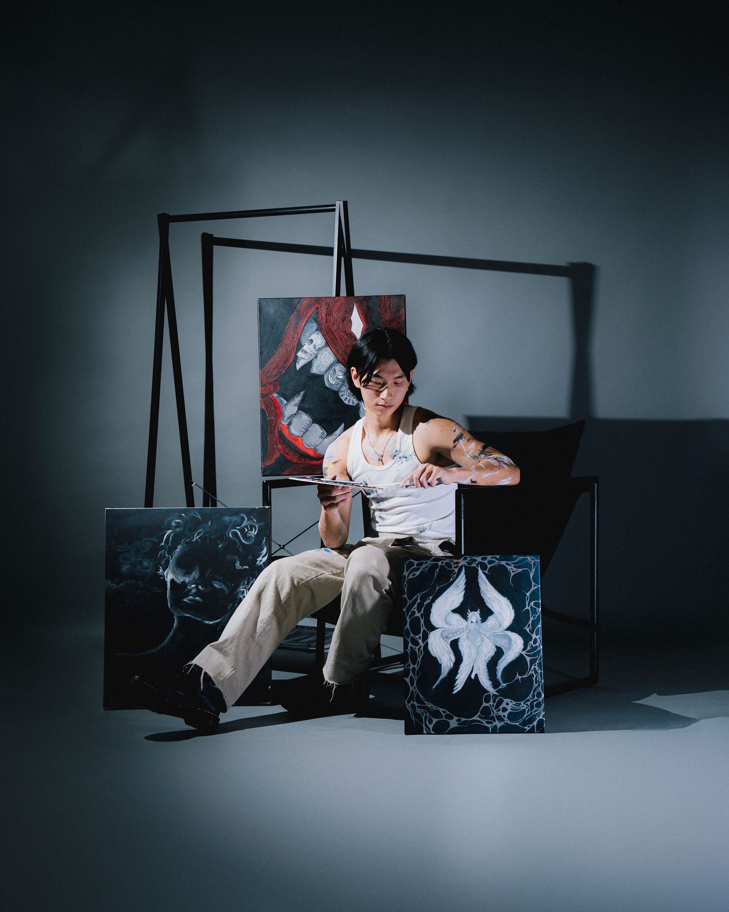 Artistic studio portrait with someone seated among geometric black frames against a dark background.