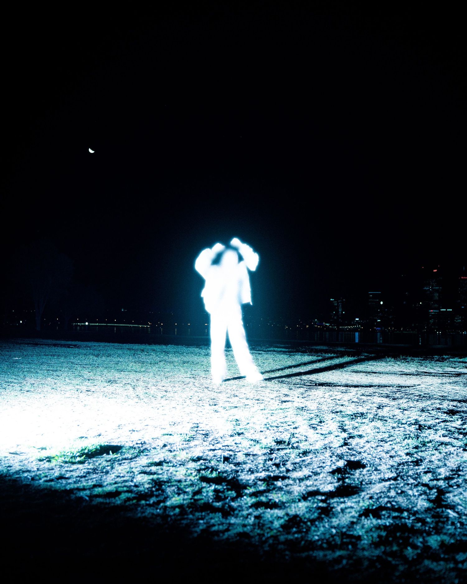 Bright glowing figure poses dramatically on snow-covered ground at night.