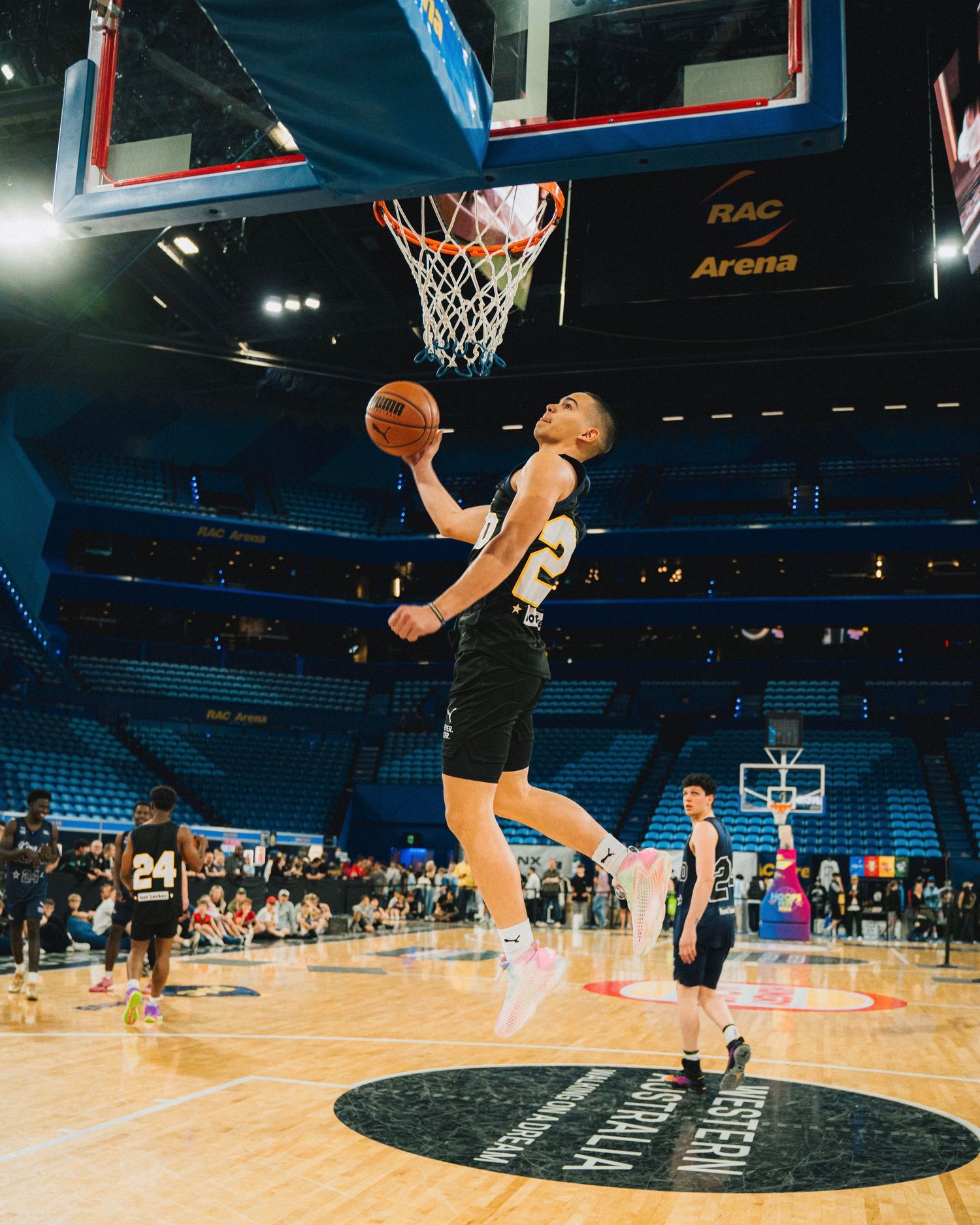 Basketball player performs a reverse layup in an indoor arena setting.